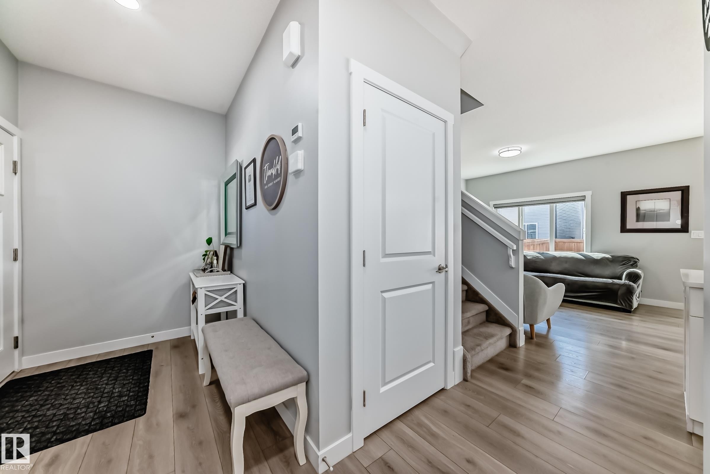 Inviting entryway featuring wood-finish flooring, a contemporary staircase with carpeted treads, white trim, and a window providing natural illumination - 19635 29 Avenue, Edmonton, AB - Indoor Photo Showing Other Room