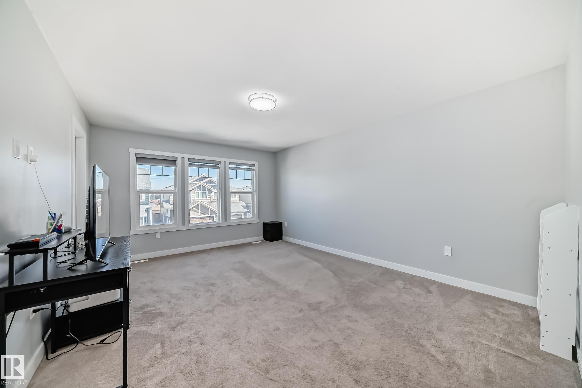 Spacious room featuring light gray walls, plush carpet flooring, and three large windows with white trim - 19635 29 Avenue, Edmonton, AB - Indoor Photo Showing Other Room