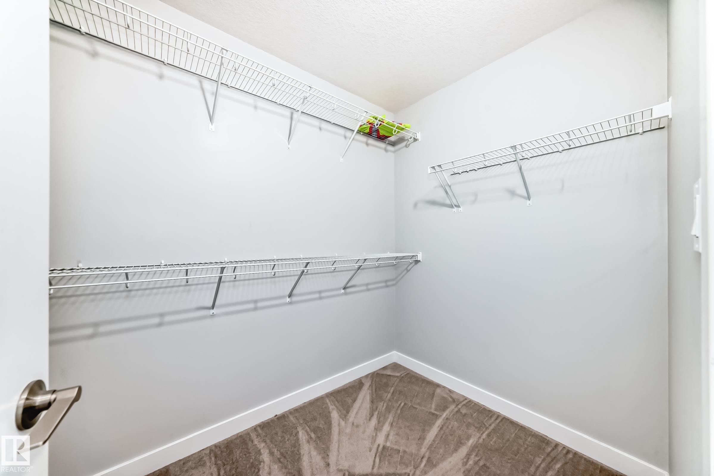 Corner closet with white wire shelving, light gray walls, and patterned carpet flooring - 19635 29 Avenue, Edmonton, AB - Indoor With Storage