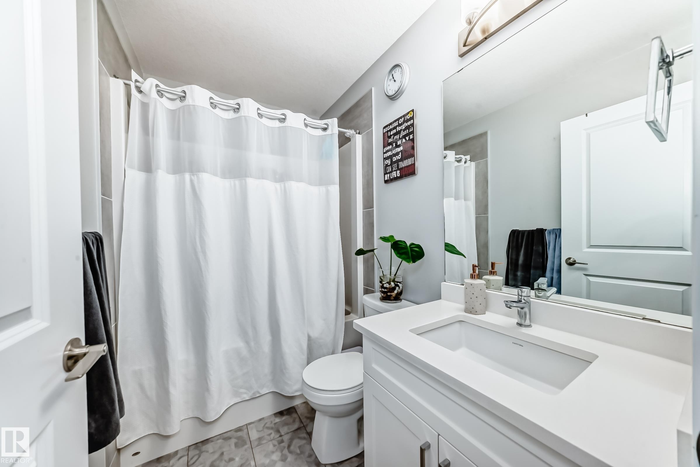 Bathroom featuring a white vanity with an integrated sink, polished chrome faucet, and a large mirror - 19635 29 Avenue, Edmonton, AB - Indoor Photo Showing Bathroom