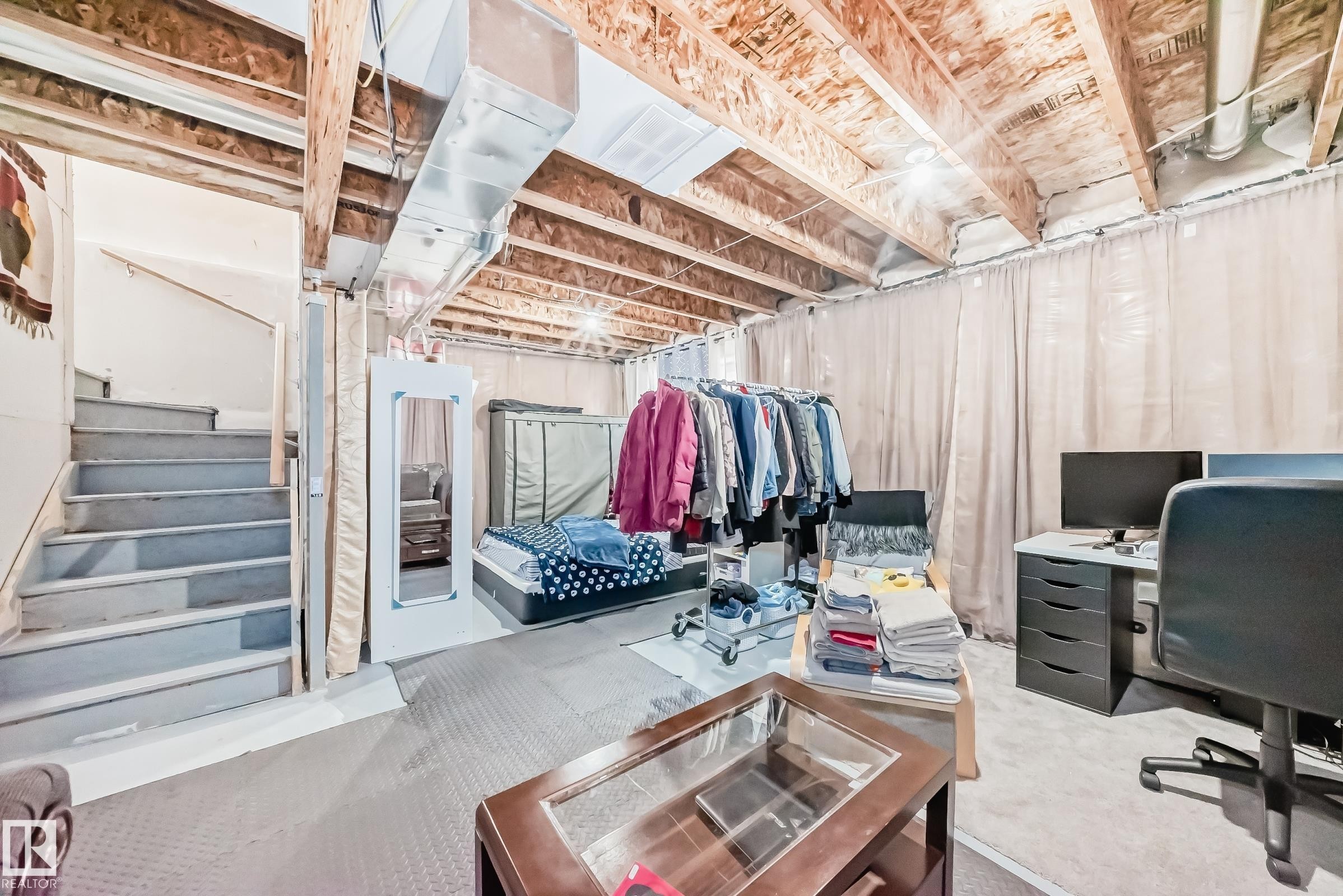 Unfinished basement area featuring exposed ceiling joists, visible ductwork, and a staircase with painted treads - 19635 29 Avenue, Edmonton, AB - Indoor