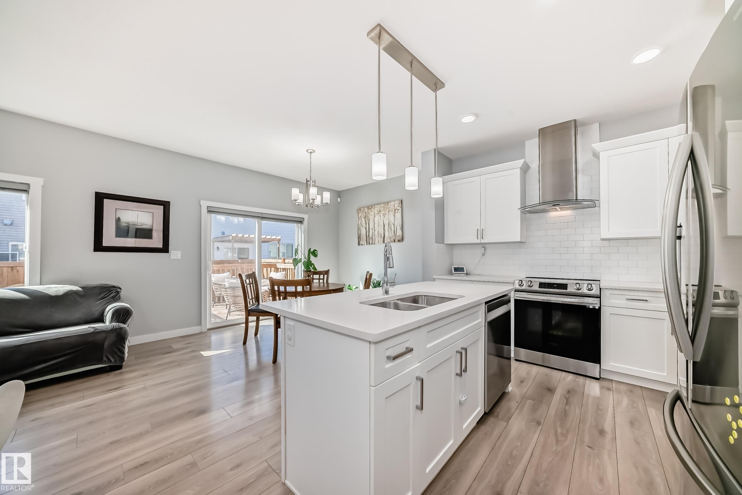Kitchen featuring a central island with an undermount double sink, white cabinetry, stainless steel appliances, and a subway tile backsplash - 19635 29 Avenue, Edmonton, AB - Indoor Photo Showing Kitchen With Double Sink With Upgraded Kitchen