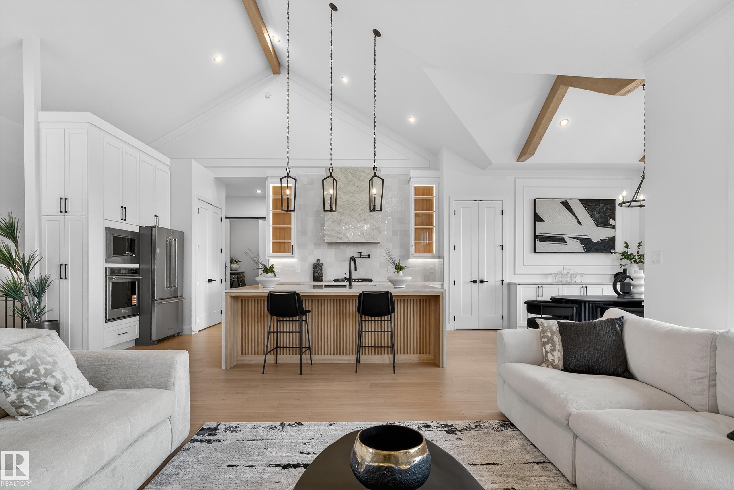 Vaulted ceiling with exposed wood beams, wood-finish flooring, and a kitchen island with pendant lighting - 711 166 Avenue, Edmonton, AB - Indoor Photo Showing Living Room
