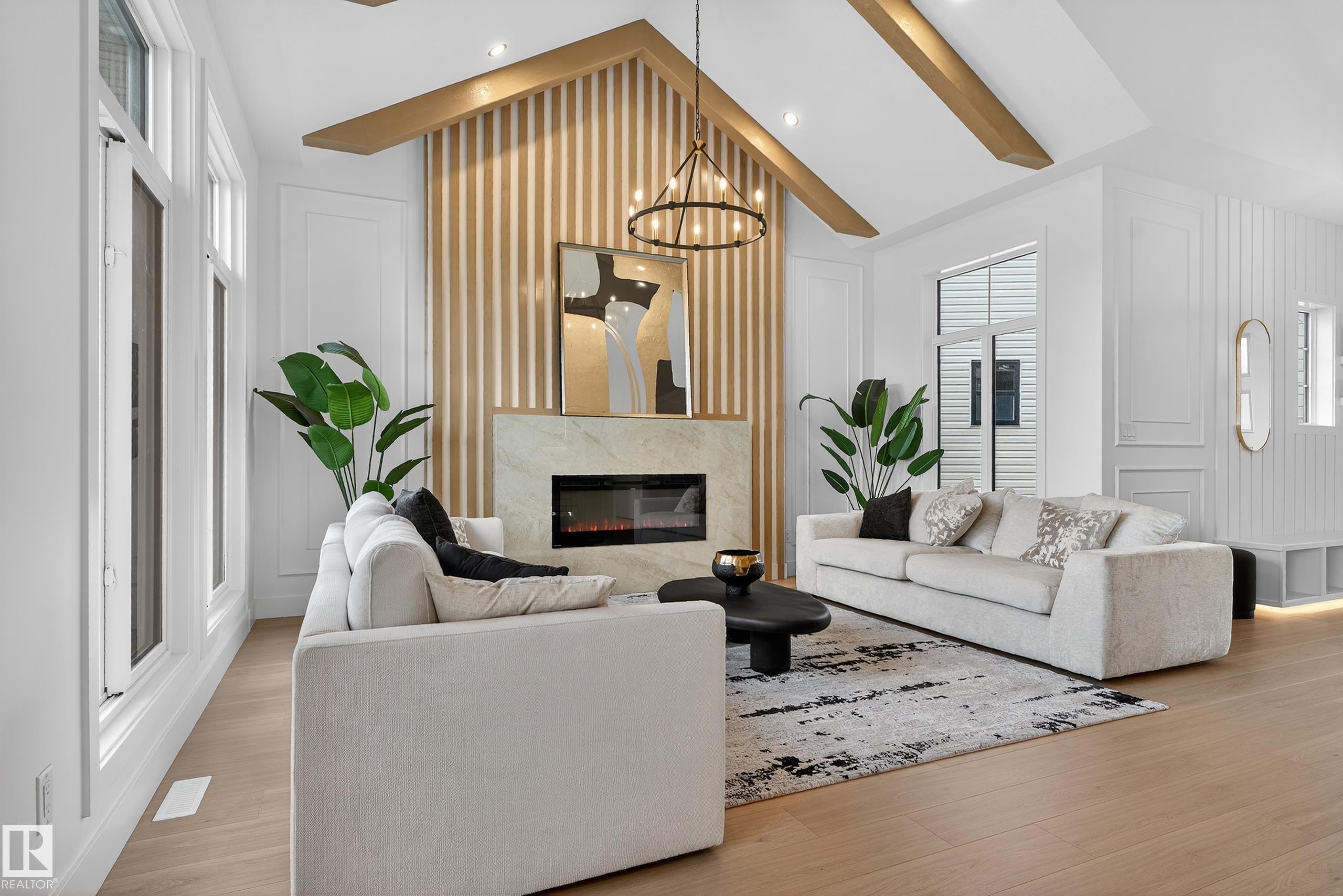 Vaulted ceiling with exposed wood beams, featuring a contemporary fireplace with a stone surround and linear firebox - 711 166 Avenue, Edmonton, AB - Indoor Photo Showing Living Room With Fireplace
