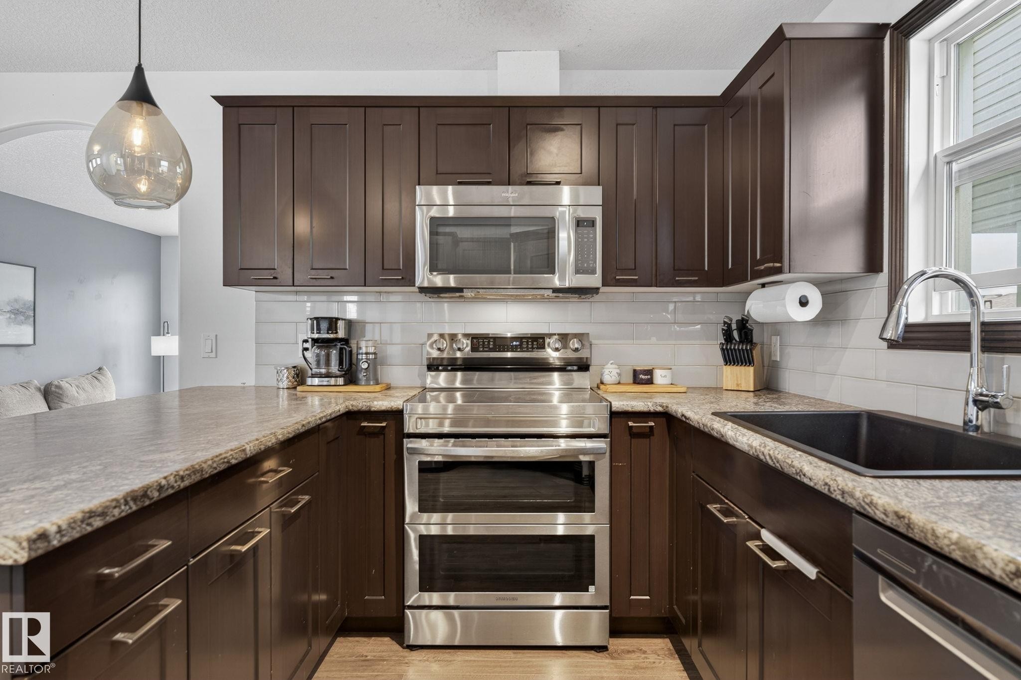 Kitchen featuring dark wood cabinetry, stainless steel appliances, a tile backsplash, and light-toned countertops - 108 Hewitt Circle, Spruce Grove, AB - Indoor Photo Showing Kitchen