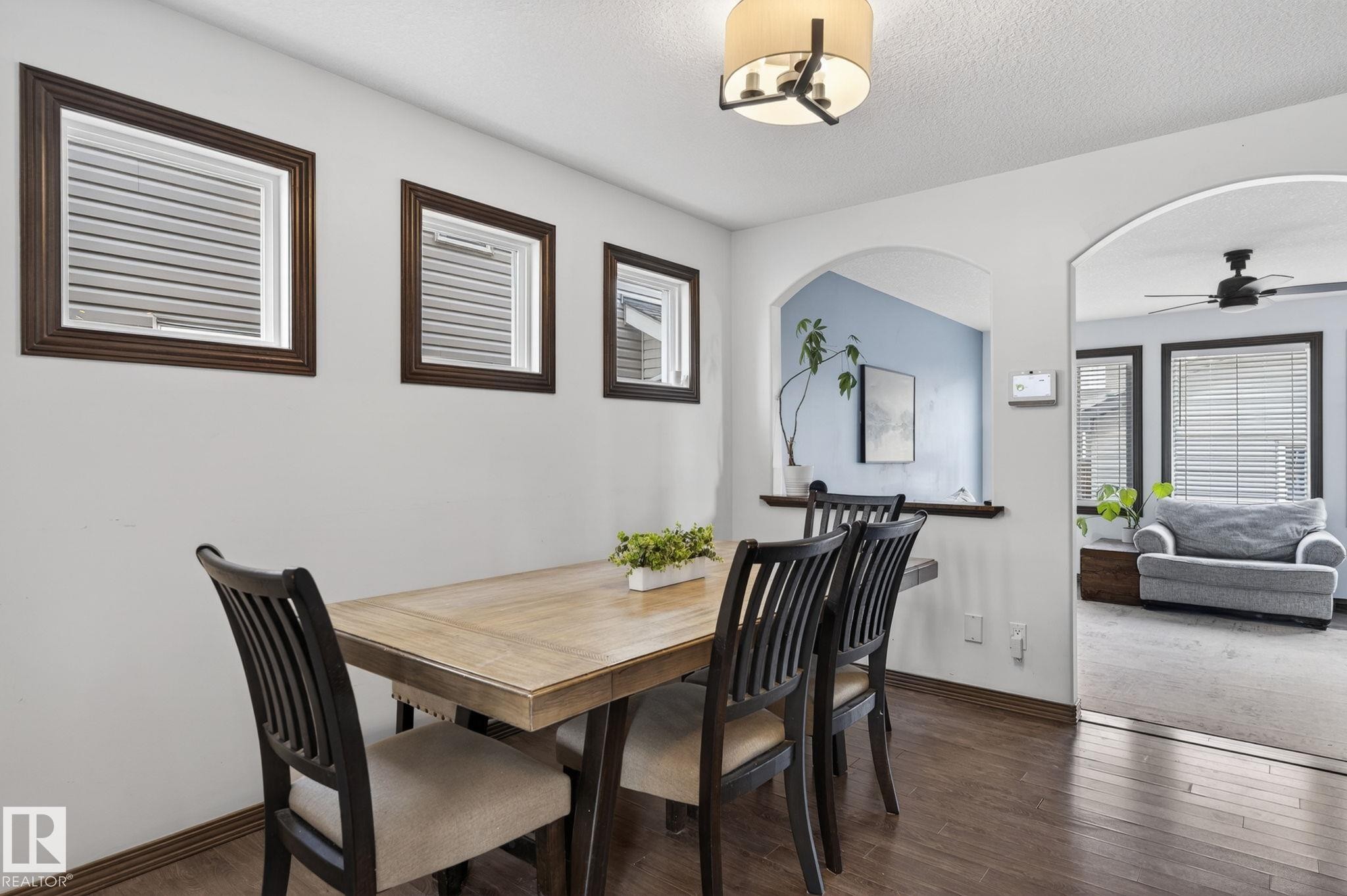 Dining area featuring wood-finish flooring, recessed windows with dark wood trim, and a contemporary ceiling light fixture - 108 Hewitt Circle, Spruce Grove, AB - Indoor Photo Showing Dining Room