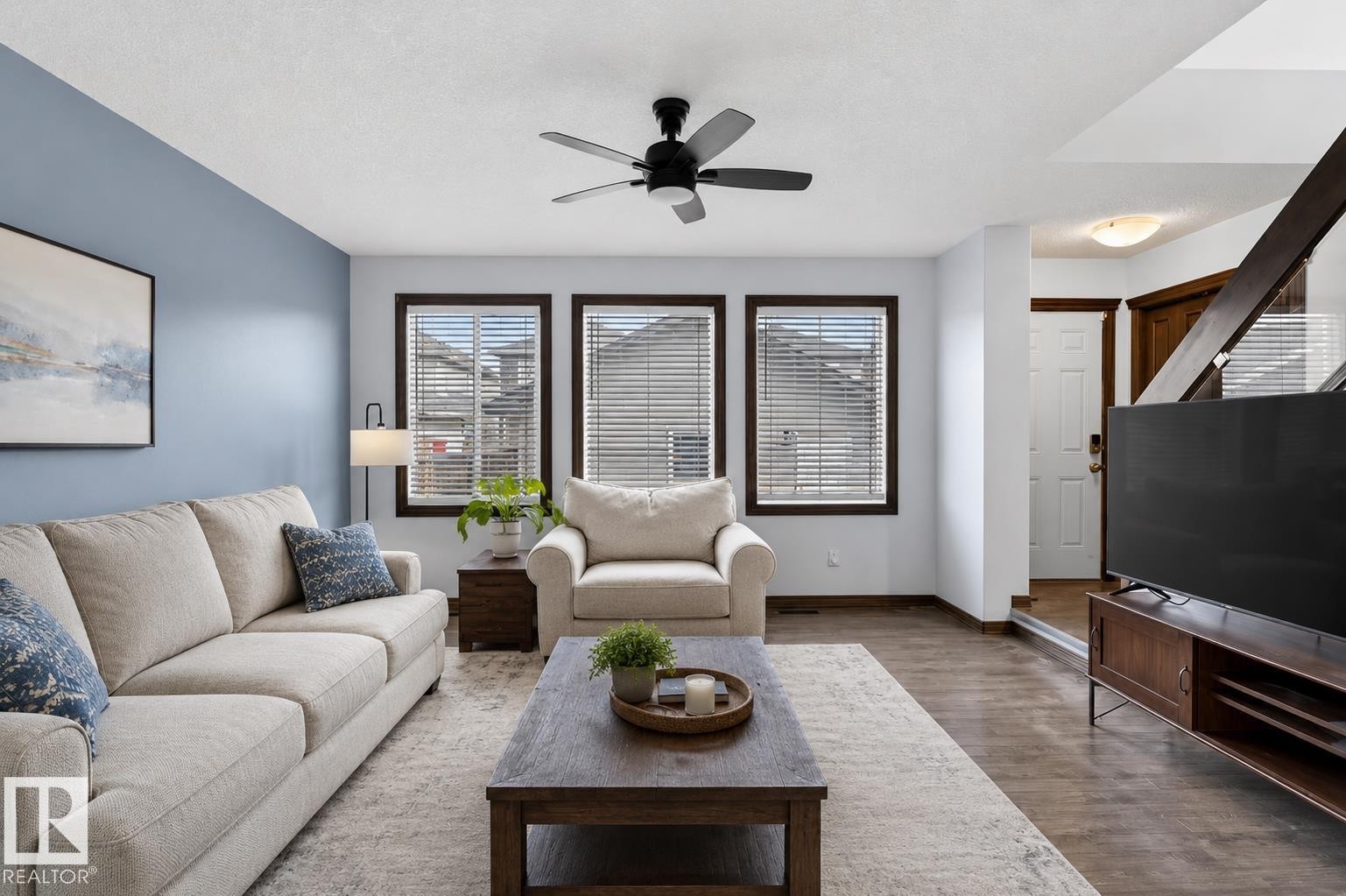 Open-concept living space featuring wood-finish flooring, a ceiling fan, and multiple windows with blinds - 108 Hewitt Circle, Spruce Grove, AB - Indoor Photo Showing Living Room