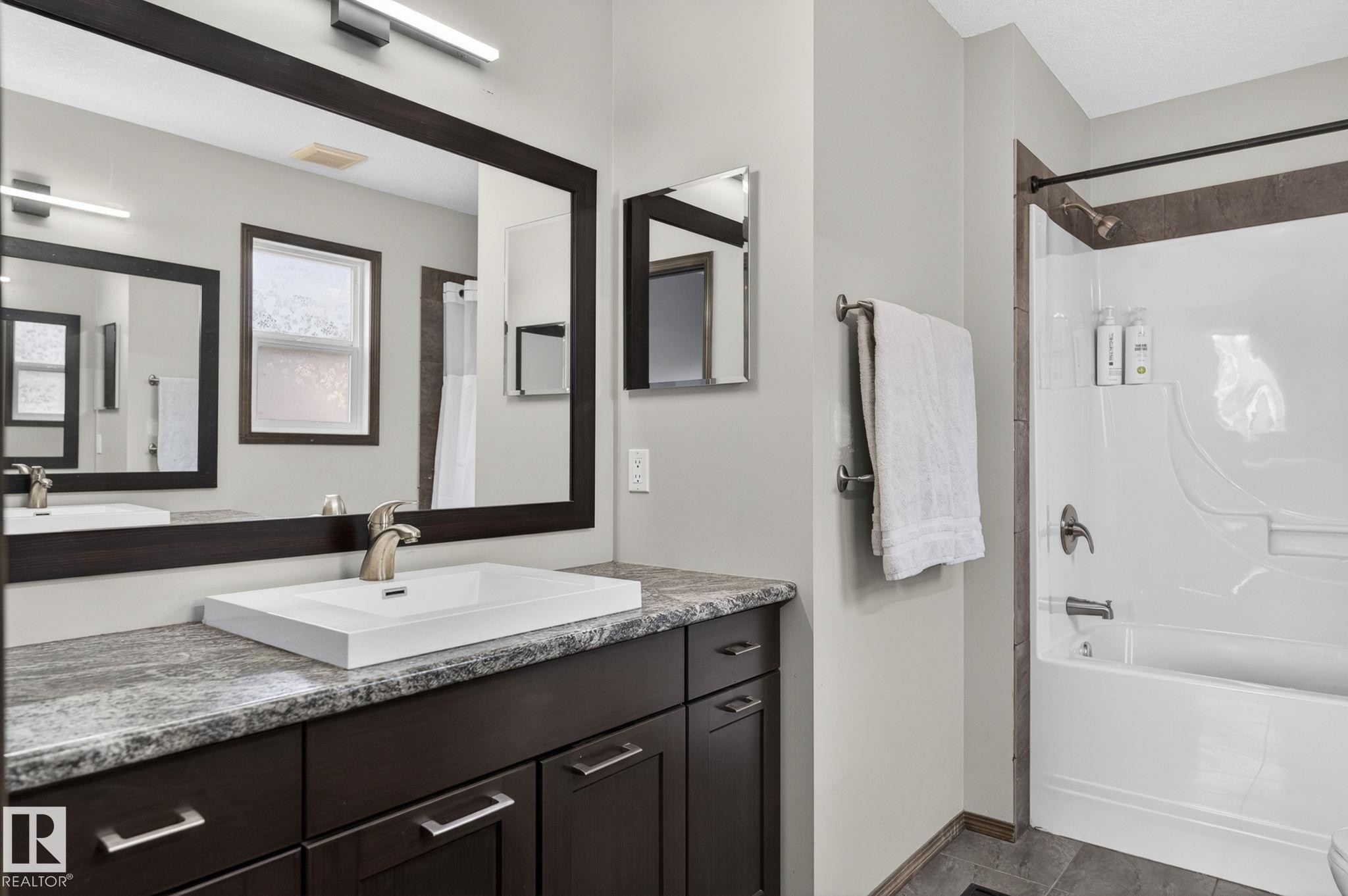Bathroom featuring a spacious vanity with a white rectangular sink, a brushed nickel faucet, and a large framed mirror - 108 Hewitt Circle, Spruce Grove, AB - Indoor Photo Showing Bathroom
