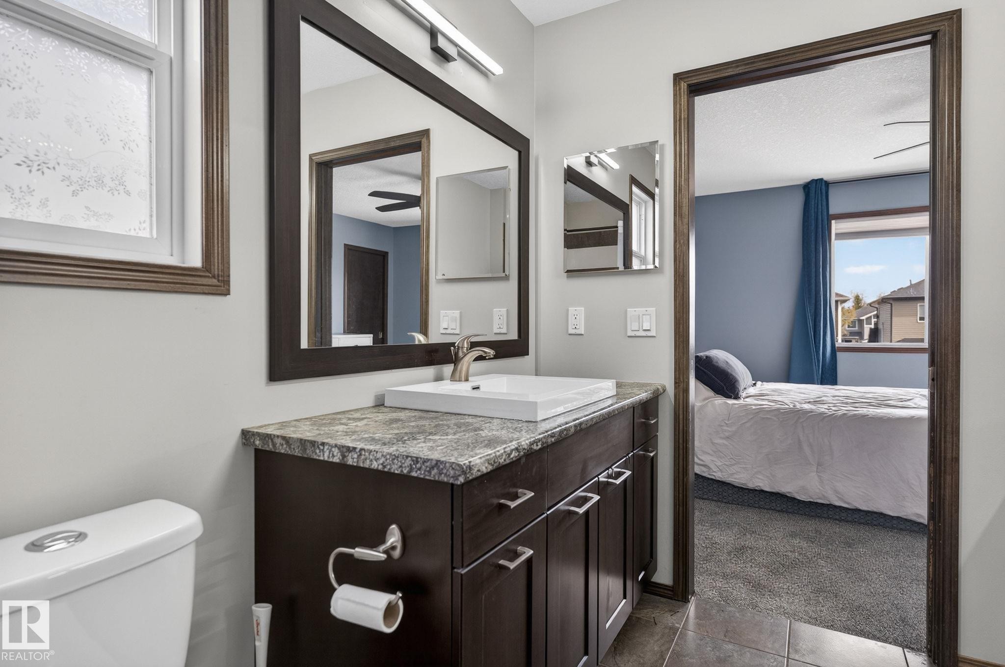 Bathroom vanity featuring a vessel sink, dark wood-finish cabinetry, and a stone-finish countertop - 108 Hewitt Circle, Spruce Grove, AB - Indoor Photo Showing Bathroom