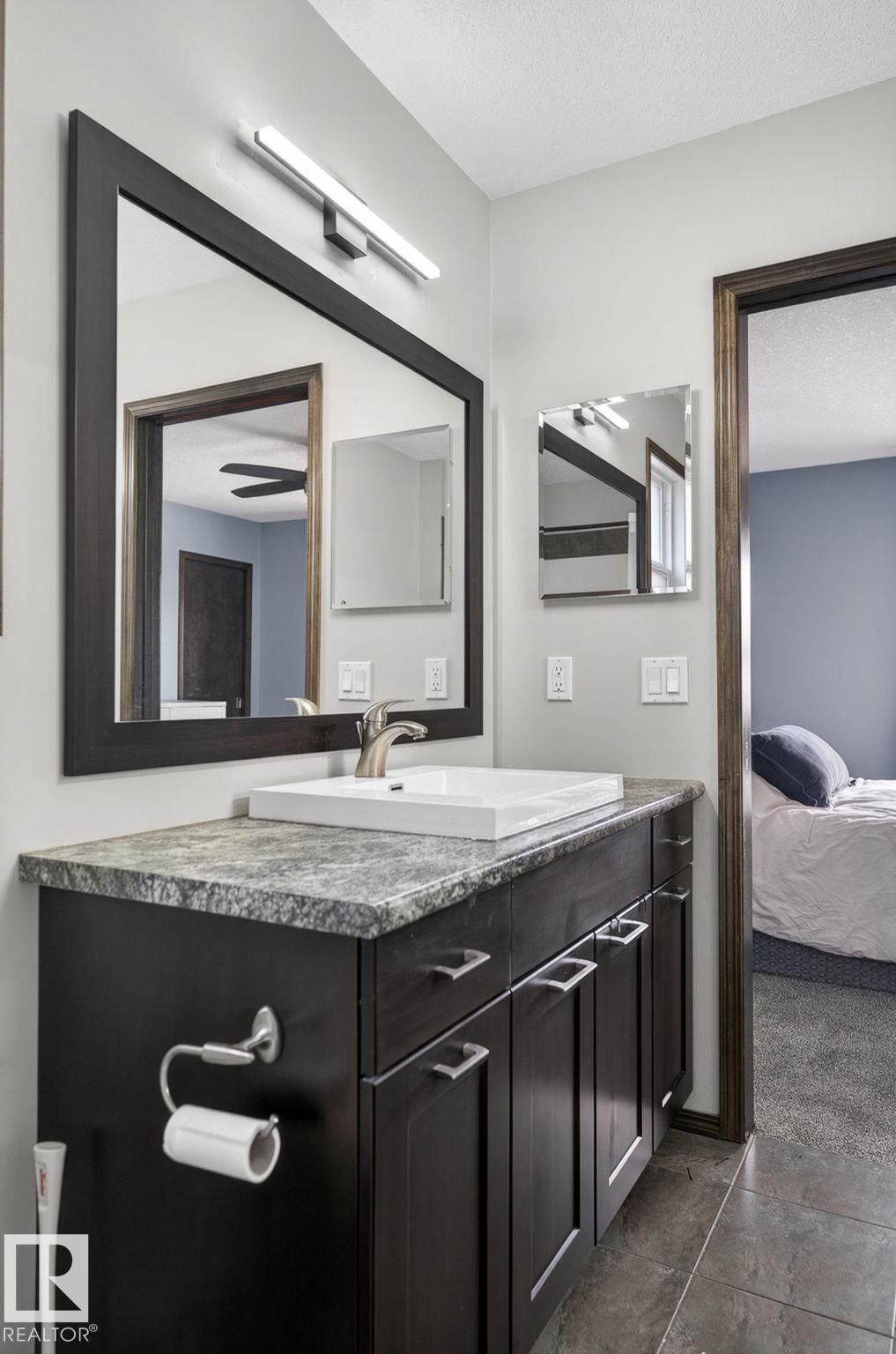 Contemporary vanity featuring dark wood-finish cabinetry, a stone-finish countertop, and a vessel sink with a brushed nickel faucet - 108 Hewitt Circle, Spruce Grove, AB - Indoor Photo Showing Bathroom