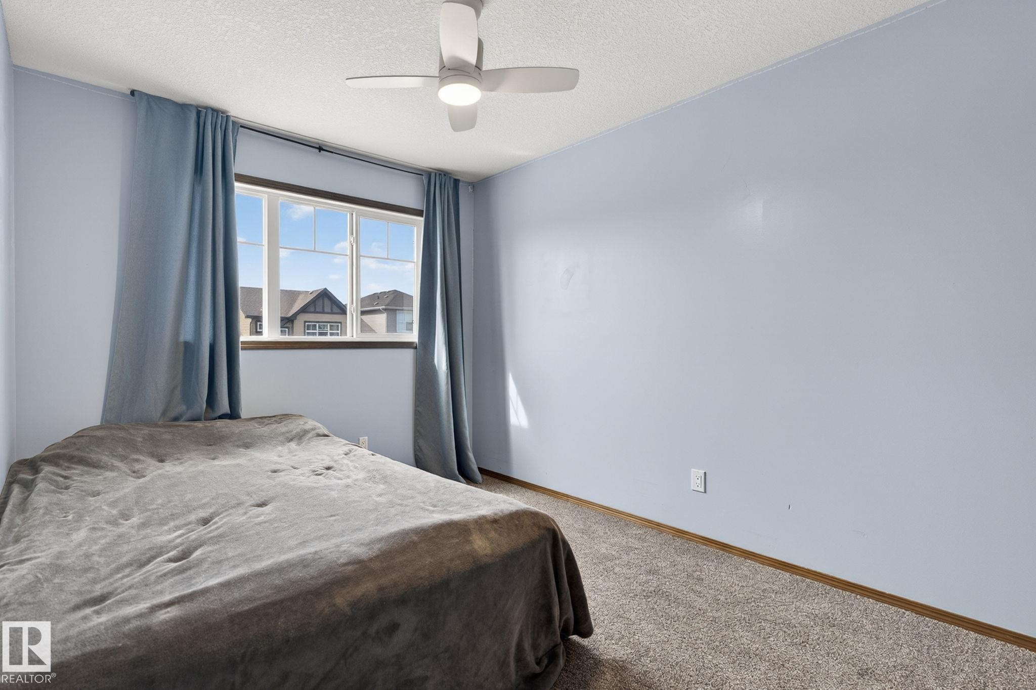 Light blue painted walls with textured carpeting, featuring a window with white framing and dark sills - 108 Hewitt Circle, Spruce Grove, AB - Indoor Photo Showing Bedroom