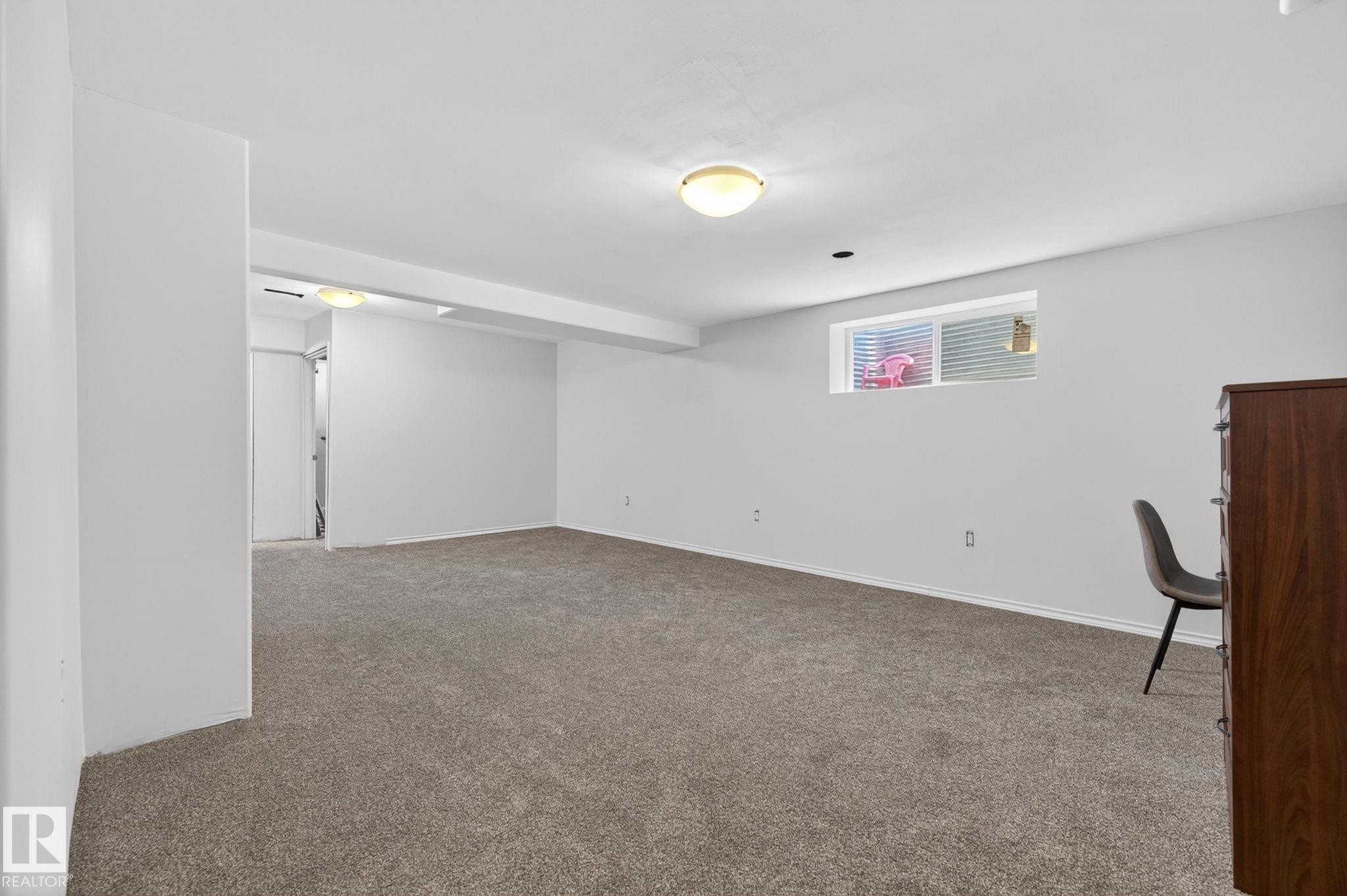 Spacious room with light gray carpeting, neutral white walls, and a visible window for natural light - 108 Hewitt Circle, Spruce Grove, AB - Indoor Photo Showing Other Room