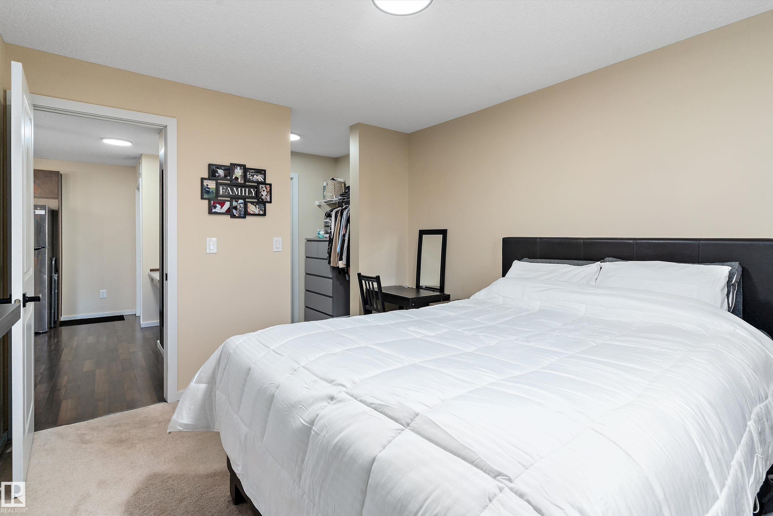 Carpeted bedroom featuring neutral wall tones and a black headboard - 122 3357 16A Avenue, Edmonton, AB - Indoor Photo Showing Bedroom