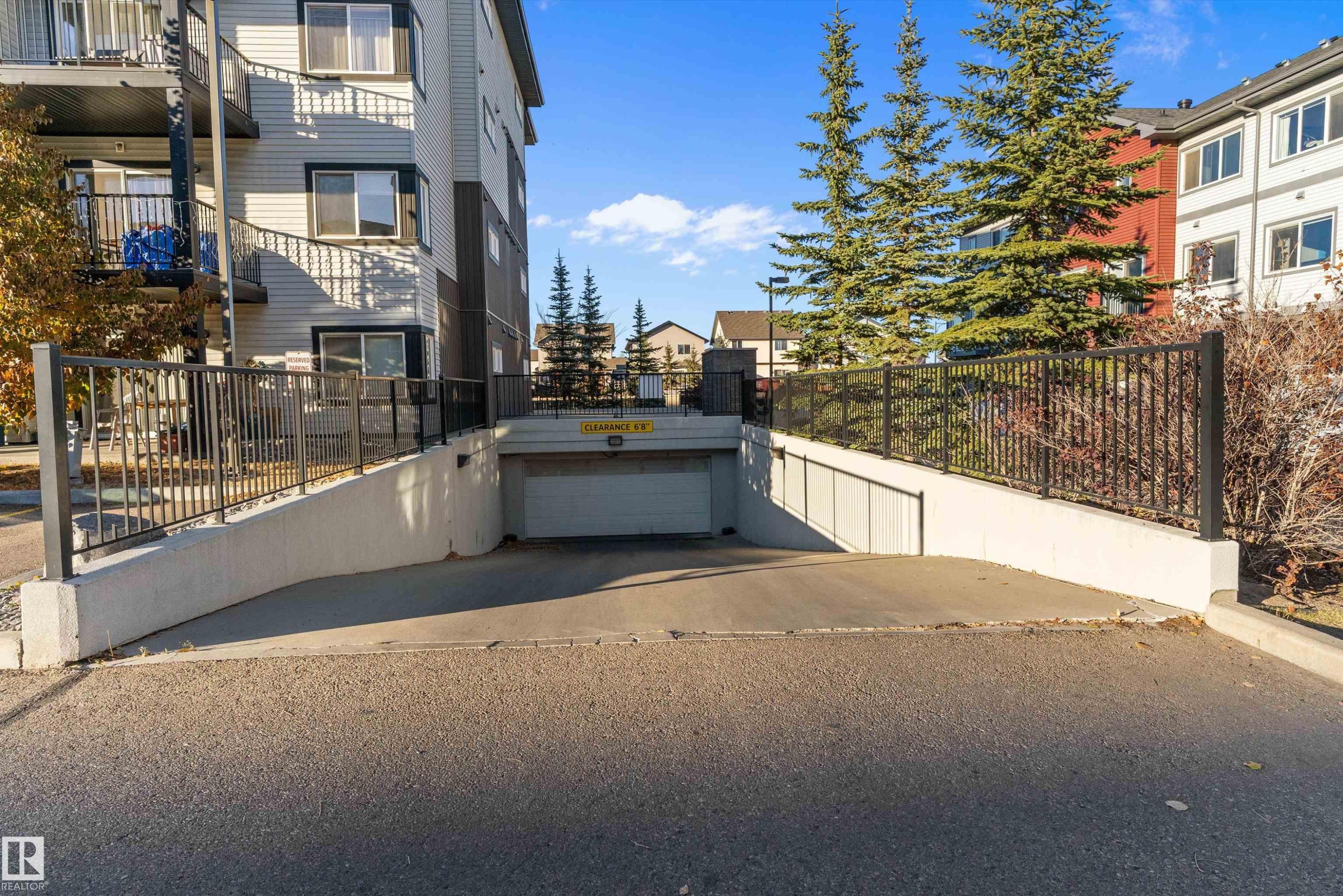 Underground parking garage entrance featuring concrete retaining walls and black metal railings - 122 3357 16A Avenue, Edmonton, AB - Outdoor