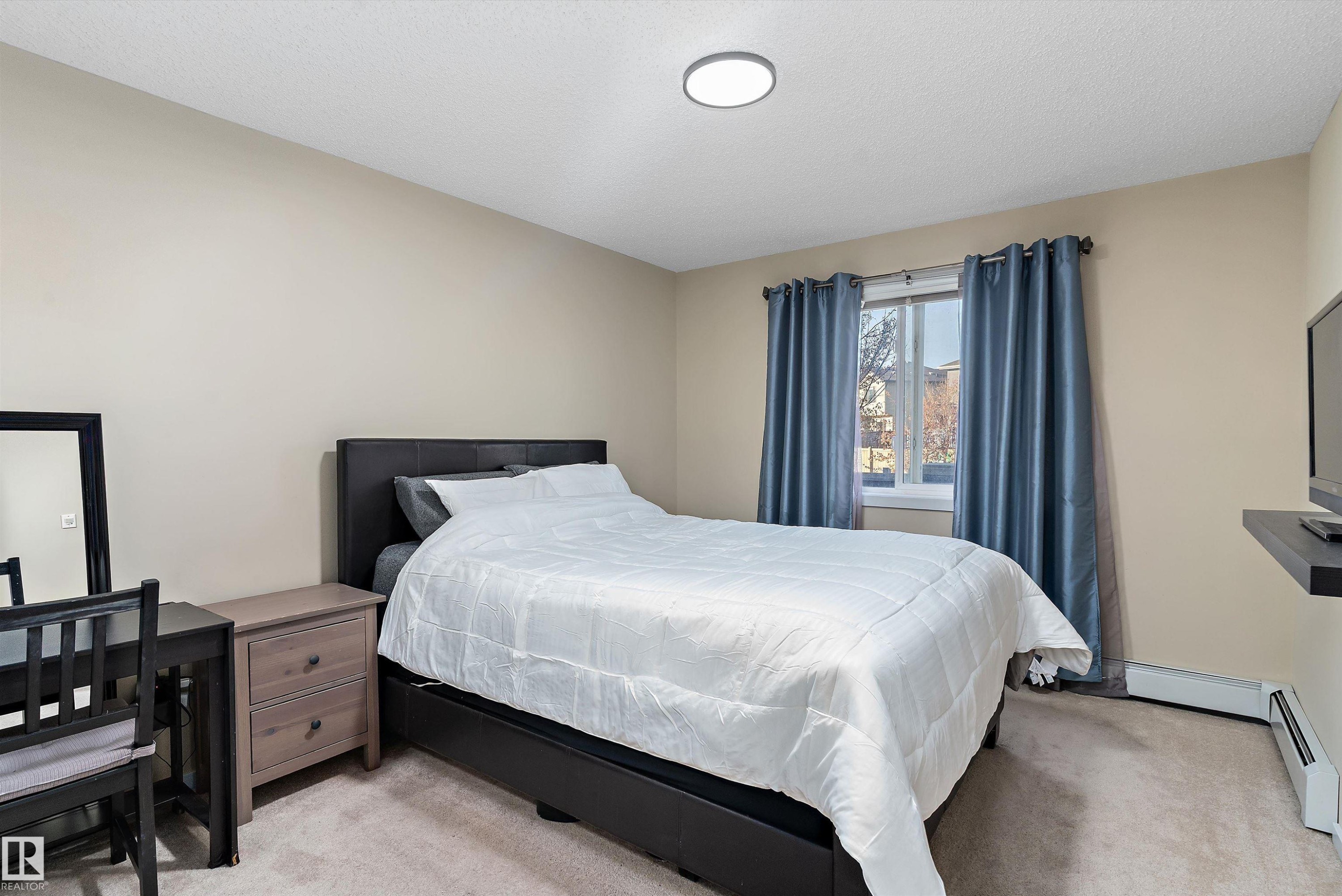Carpeted room with a double window, light tan walls, and a ceiling-mounted flush light fixture - 122 3357 16A Avenue, Edmonton, AB - Indoor Photo Showing Bedroom