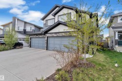 Contemporary two-story residence featuring a dual-tone exterior with white siding and dark gray accents -