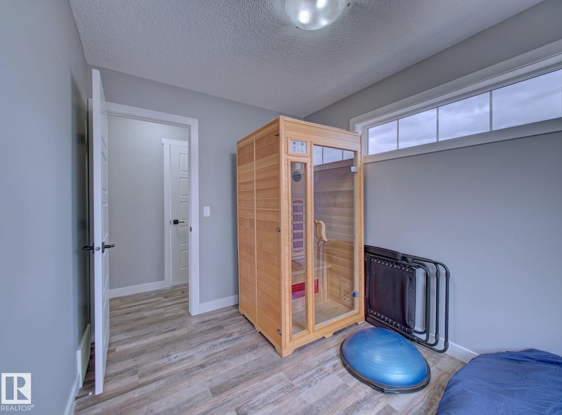 Room featuring wood-finish flooring, light grey walls, and white trim - 11 165 Cy Becker Boulevard, Edmonton, AB - Indoor