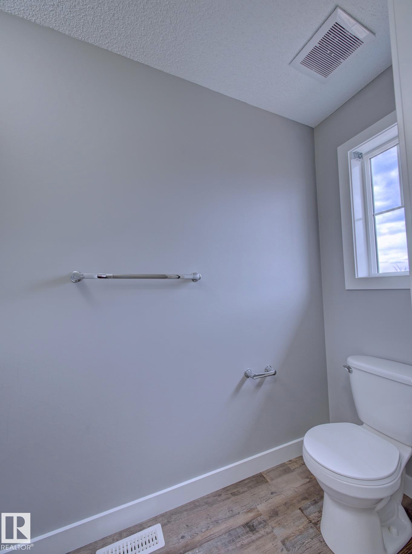 Powder room featuring light gray walls, white baseboards, and wood-finish flooring - 11 165 Cy Becker Boulevard, Edmonton, AB - Indoor Photo Showing Bathroom