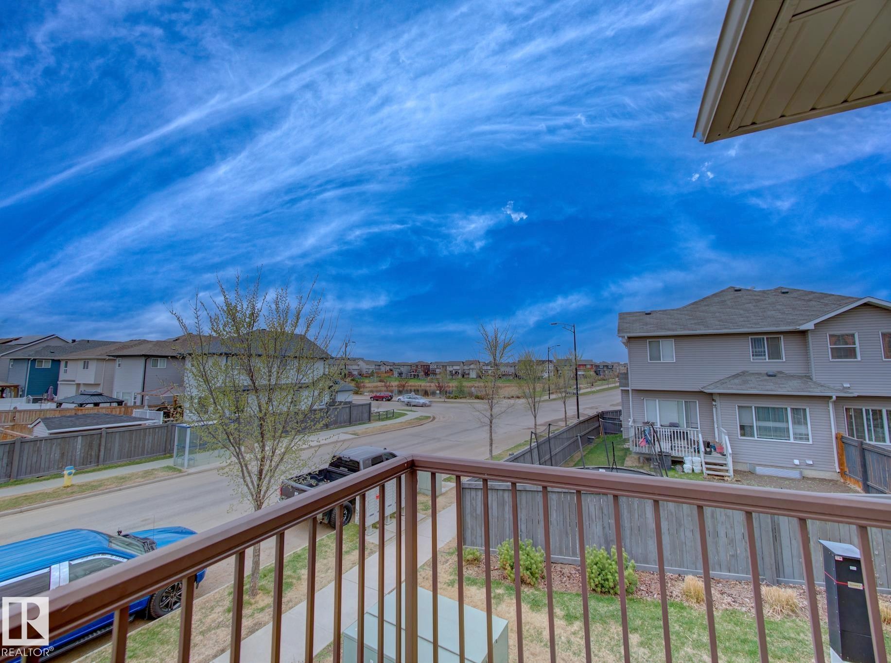 Balcony with metal railing offering elevated perspectives of the neighborhood street and residential properties - 11 165 Cy Becker Boulevard, Edmonton, AB - Outdoor