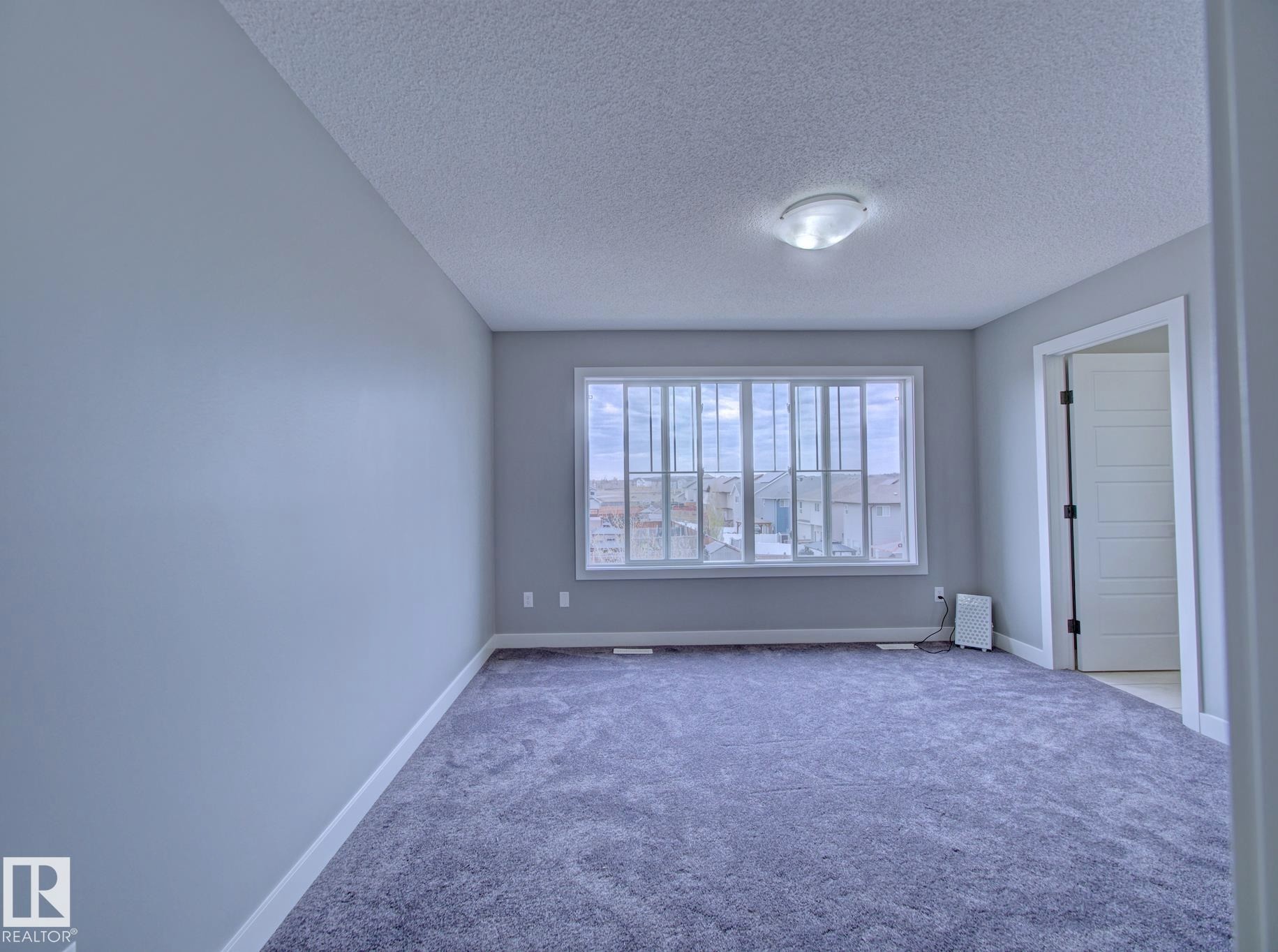 Spacious room featuring broadloom carpeting and light gray wall paint - 11 165 Cy Becker Boulevard, Edmonton, AB - Indoor Photo Showing Other Room