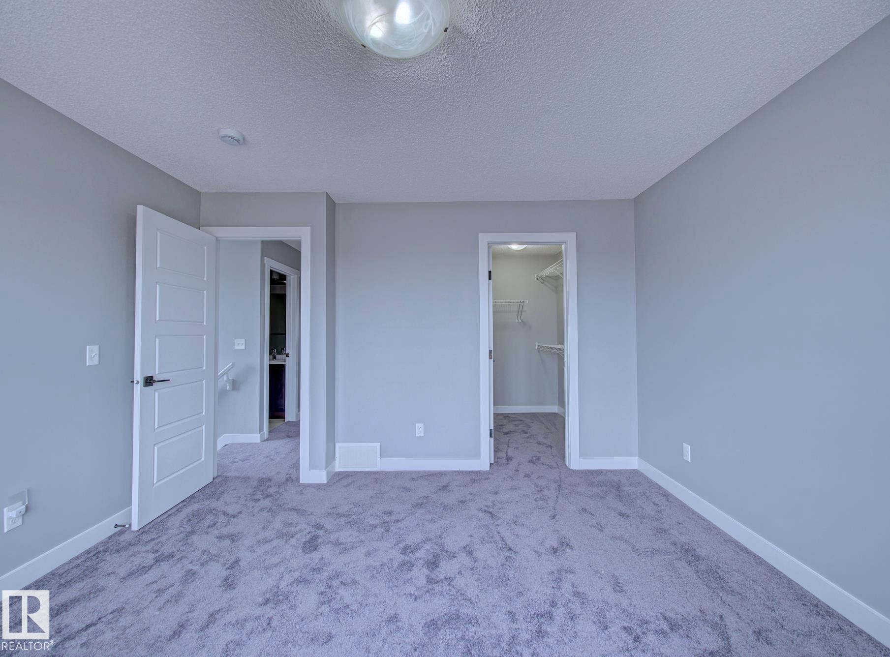 Carpeted room featuring light gray wall paint, white baseboards, and a semi-flush mount ceiling light - 11 165 Cy Becker Boulevard, Edmonton, AB - Indoor