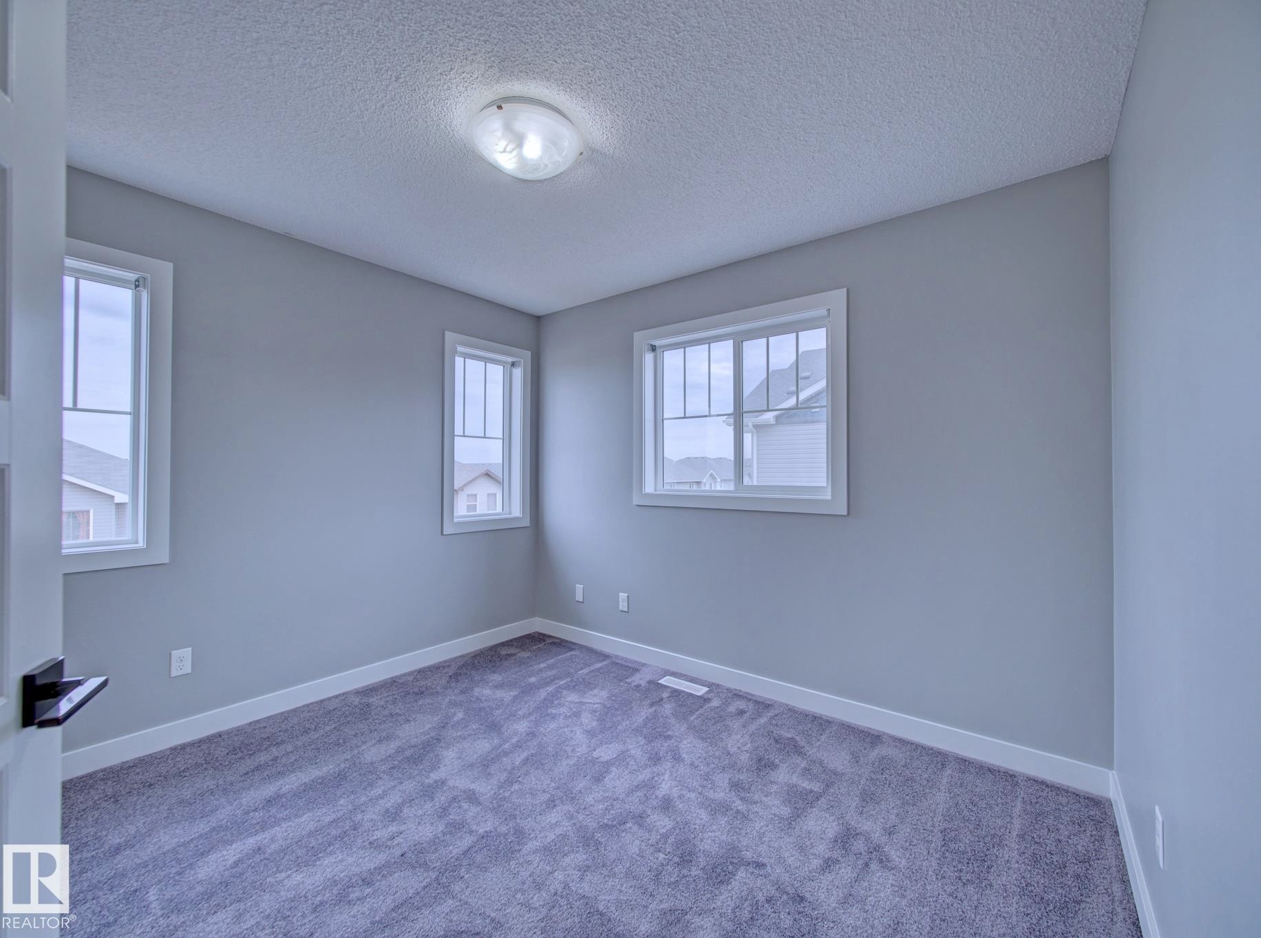 3rd Bedroom Carpeted interior room featuring light gray walls, white trim, and multiple windows - 11 165 Cy Becker Boulevard, Edmonton, AB - Indoor Photo Showing Other Room