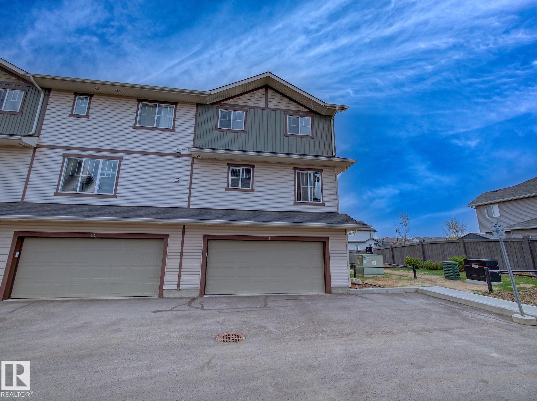 Multi-story townhouse with light-colored siding and dark trim accents - 11 165 Cy Becker Boulevard, Edmonton, AB - Outdoor