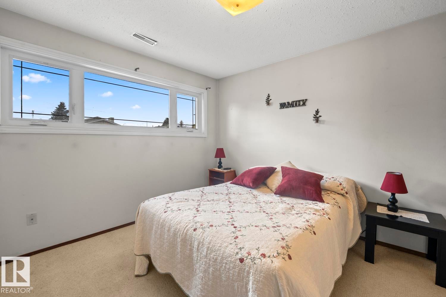 Room featuring a large multi-pane window, neutral-toned walls, and wall-to-wall carpeting - 1304 12 Street, Cold Lake, AB - Indoor Photo Showing Bedroom