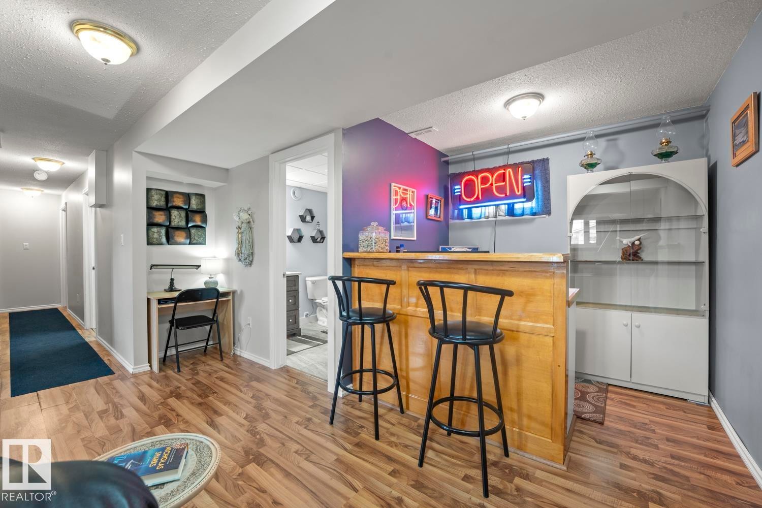 Entertainment area featuring a built-in bar, wood-finish flooring, recessed lighting, and an adjacent built-in display cabinet - 1304 12 Street, Cold Lake, AB - Indoor
