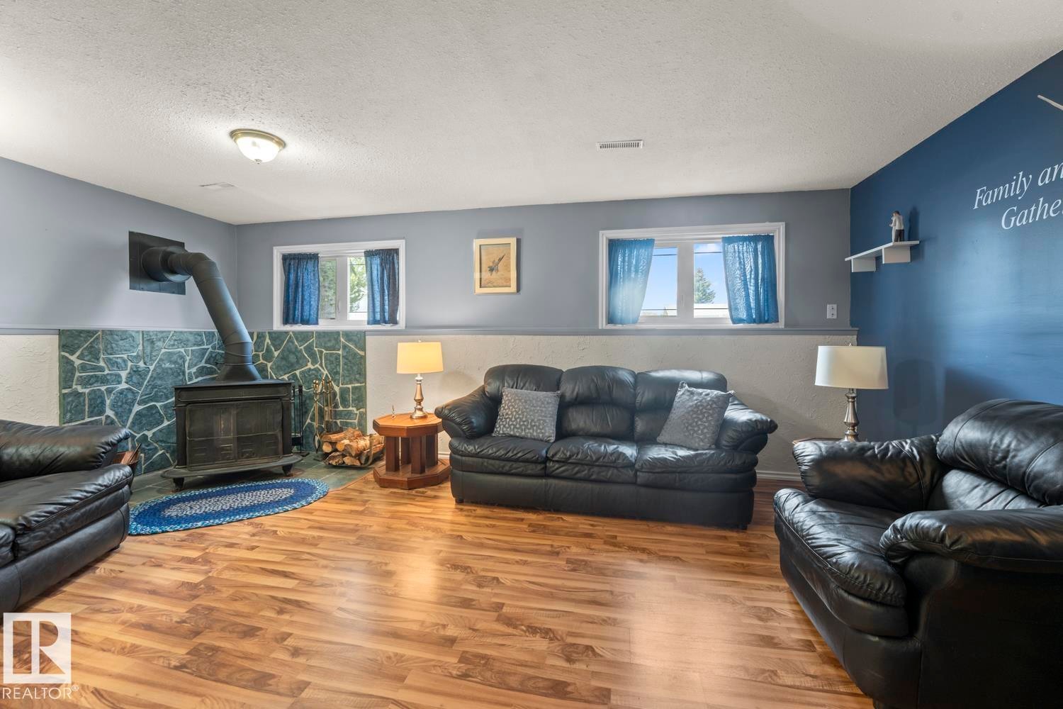 Living area featuring wood-finish flooring and a corner wood stove with a stone surround - 1304 12 Street, Cold Lake, AB - Indoor Photo Showing Living Room With Fireplace