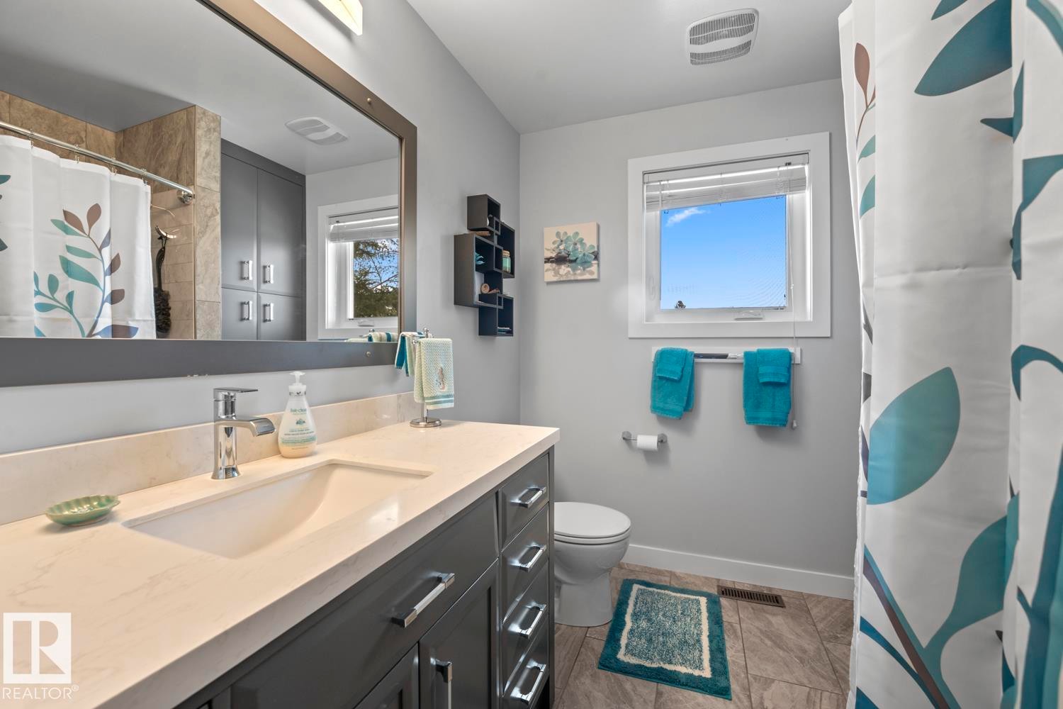Bathroom featuring a spacious vanity with an integrated sink, polished chrome faucet, and quartz-finish countertop - 1304 12 Street, Cold Lake, AB - Indoor Photo Showing Bathroom