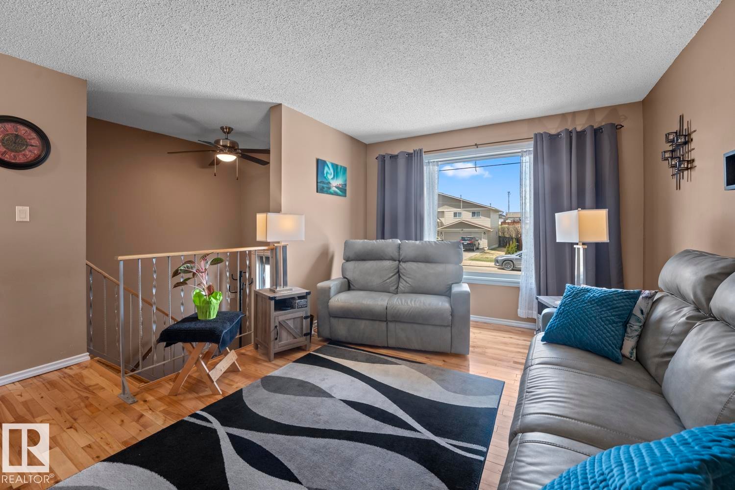 Spacious room featuring wood-finish flooring, neutral-toned walls, a large window with white trim, and a ceiling fan - 1304 12 Street, Cold Lake, AB - Indoor Photo Showing Living Room