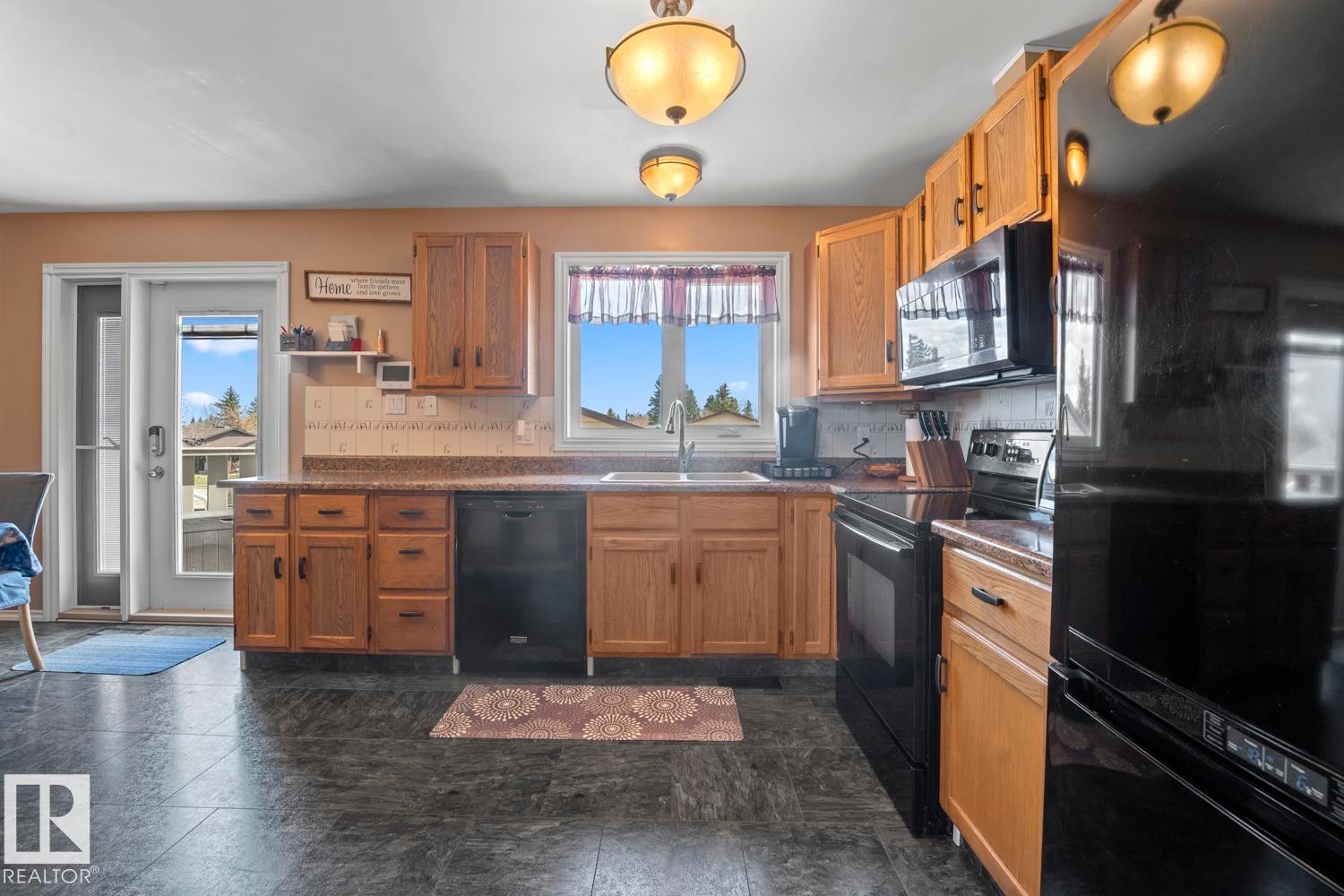Well-appointed kitchen featuring wood cabinetry, black appliances, a double basin sink, and ample counter space - 1304 12 Street, Cold Lake, AB - Indoor Photo Showing Kitchen