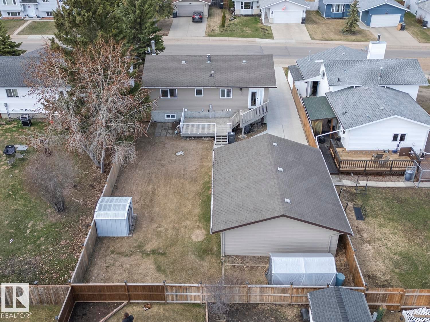 Spacious backyard featuring a wooden privacy fence, detached garage, and a raised wooden deck - 1304 12 Street, Cold Lake, AB - Outdoor