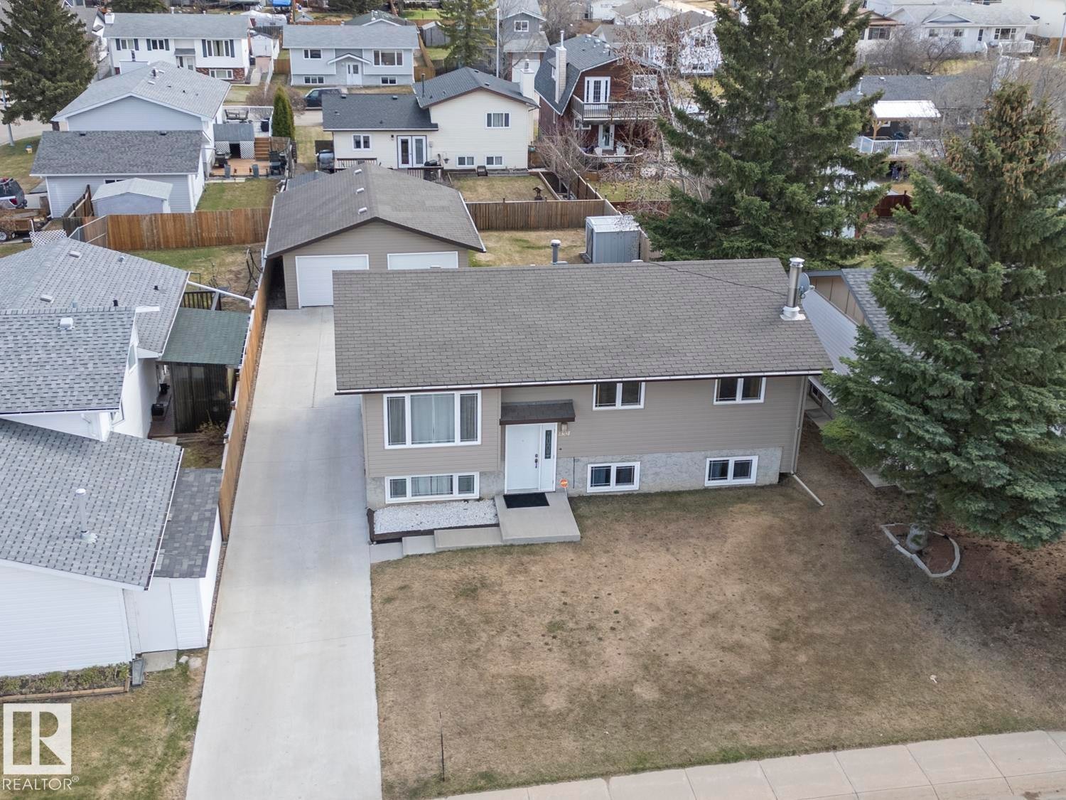 Bi-level residence featuring a neutral-toned exterior with stone veneer accents and a dark shingle roof - 1304 12 Street, Cold Lake, AB - Outdoor