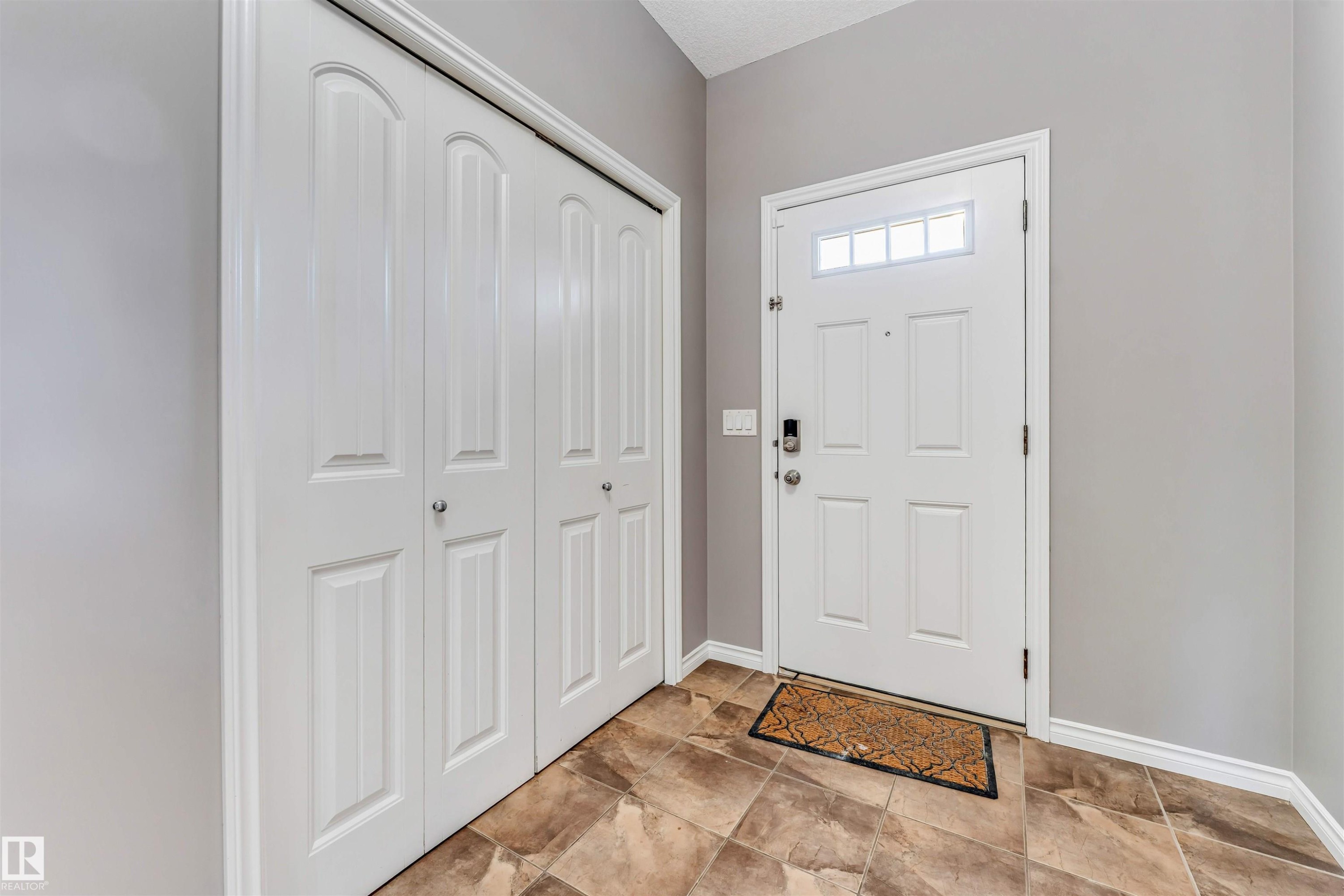 Entryway featuring a white paneled door with transom windows, a smart lock, and neutral-toned walls - 2138 32B Street, Edmonton, AB - Indoor Photo Showing Other Room