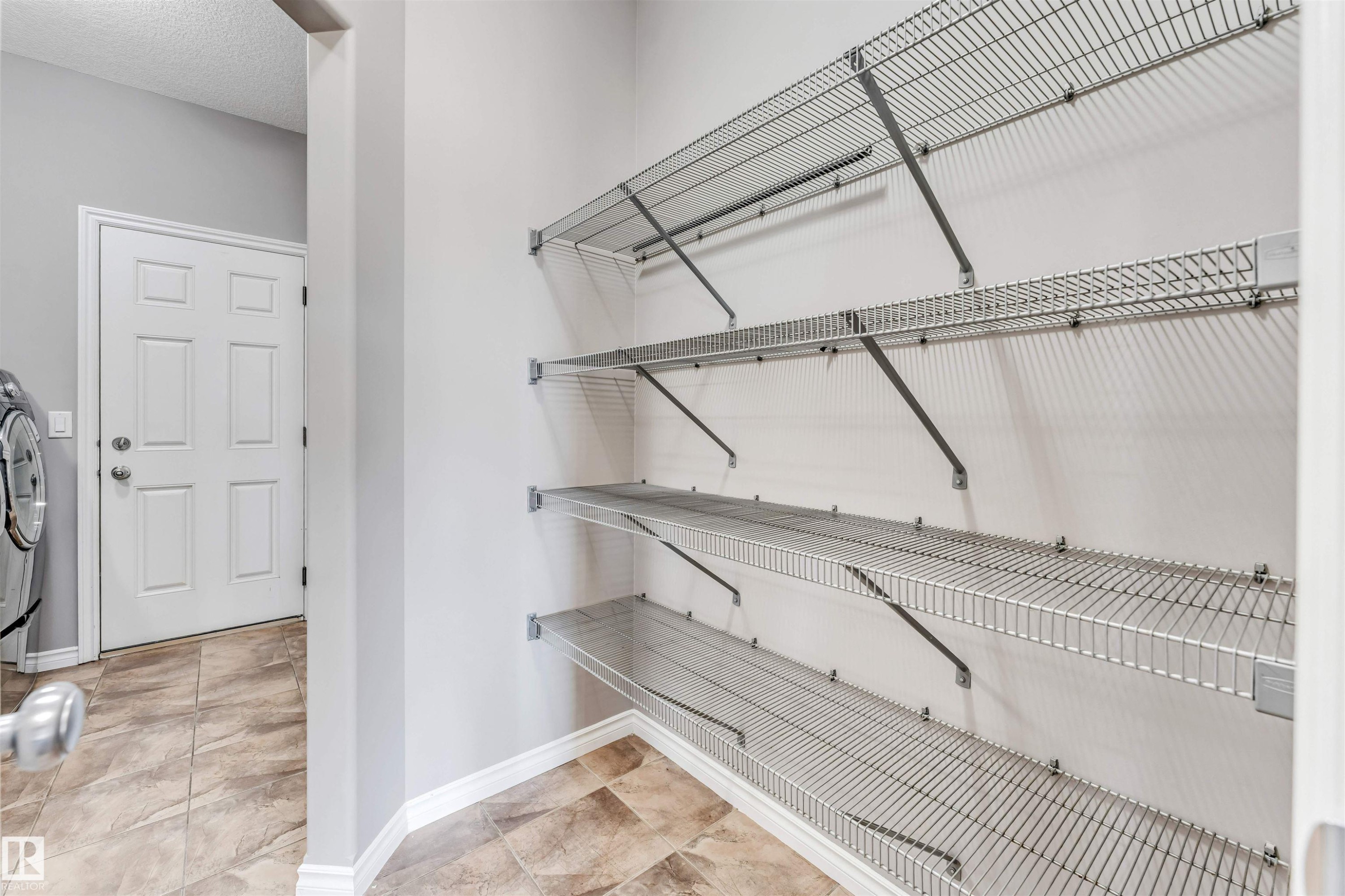 Corner pantry featuring multiple wire shelving units, light gray walls, and tile flooring - 2138 32B Street, Edmonton, AB - Indoor With Storage