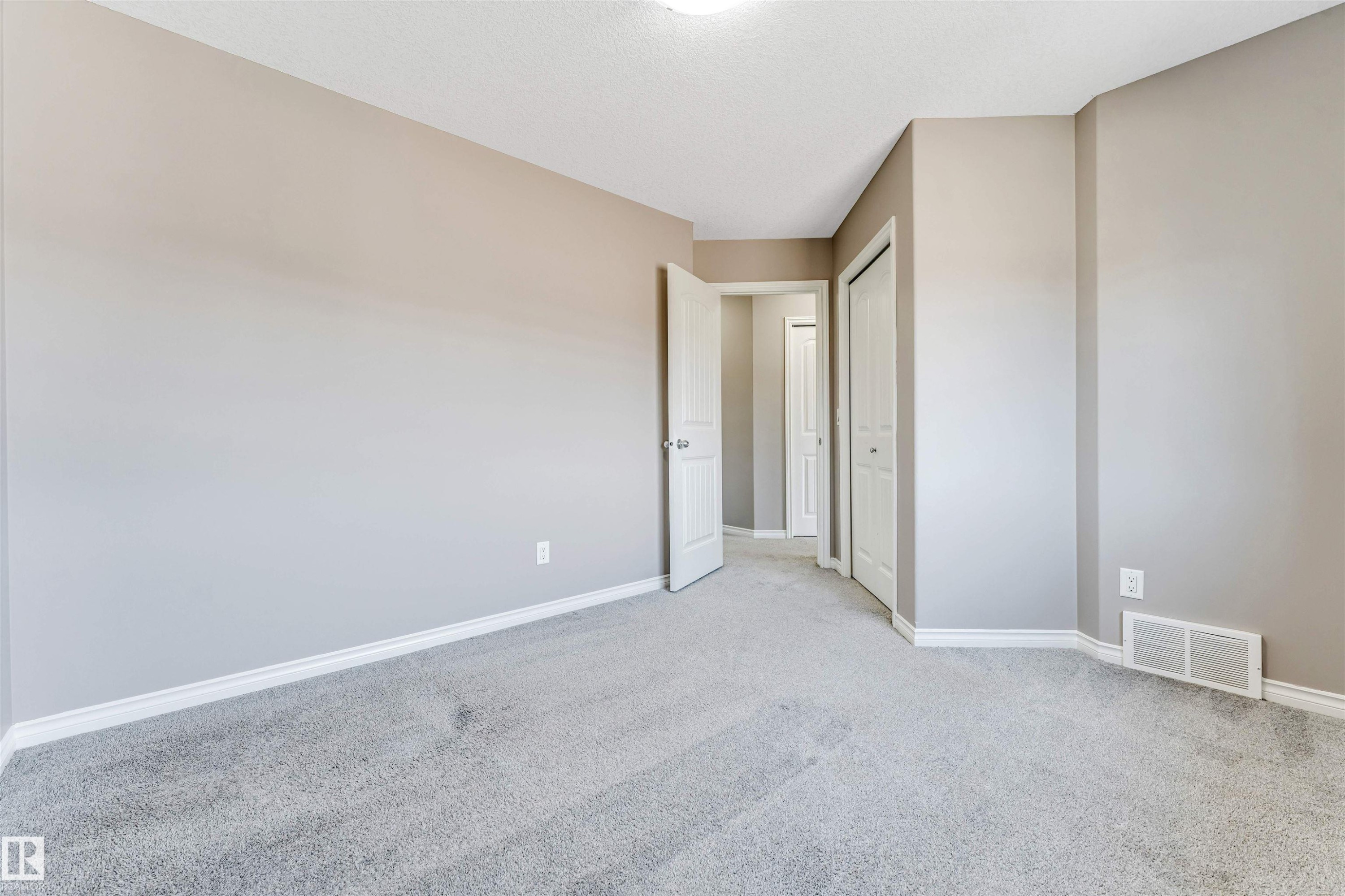Neutral-toned interior room featuring light gray carpet, white baseboards, and a white ceiling with a flush-mount light fixture - 2138 32B Street, Edmonton, AB - Indoor Photo Showing Other Room