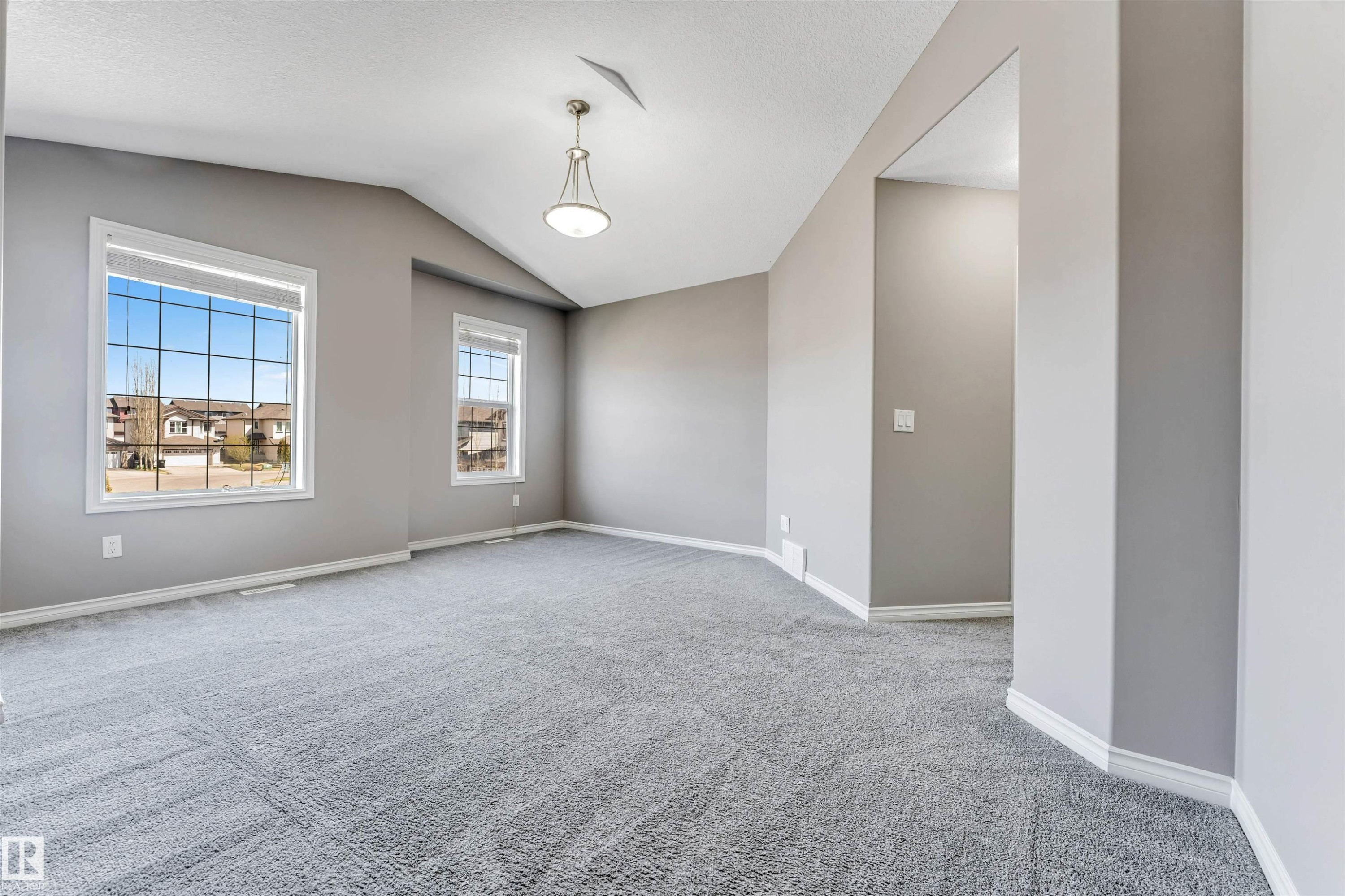 Spacious room featuring vaulted ceilings, plush grey carpeting, and two multi-pane windows - 2138 32B Street, Edmonton, AB - Indoor Photo Showing Other Room
