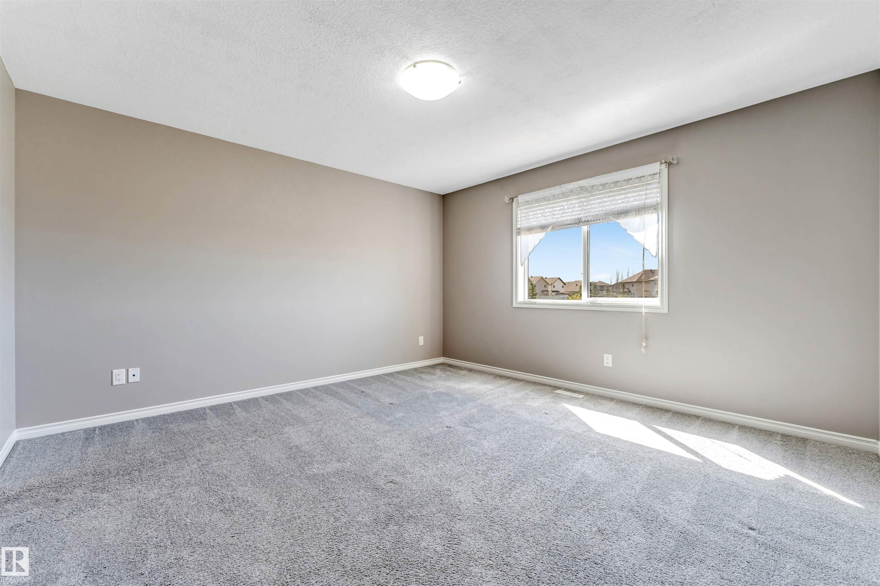 Spacious room featuring neutral wall tones, gray carpet flooring, a window with horizontal blinds, and a flush-mount ceiling light fixture - 2138 32B Street, Edmonton, AB - Indoor Photo Showing Other Room