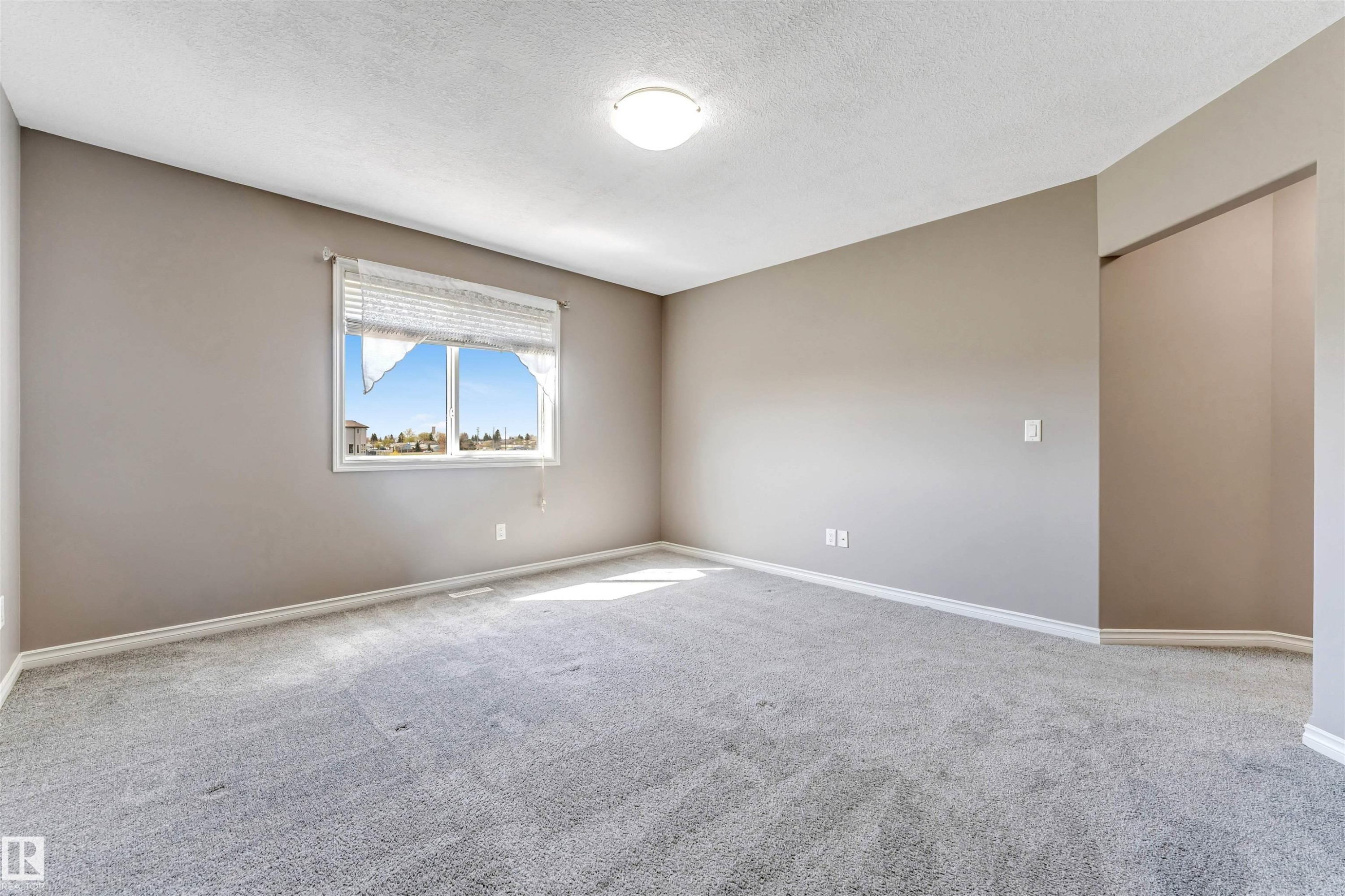 Spacious room featuring neutral-toned walls, light grey carpeting, white baseboards, and a bright window - 2138 32B Street, Edmonton, AB - Indoor Photo Showing Other Room