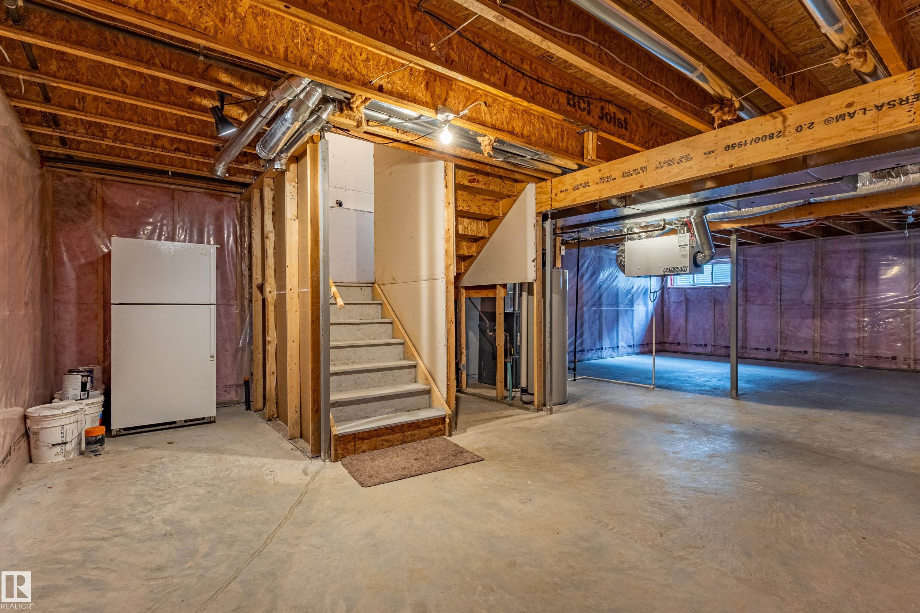 Unfinished basement featuring exposed wood joists, concrete flooring, and a carpeted staircase - 17715 6 Avenue, Edmonton, AB - Indoor Photo Showing Basement