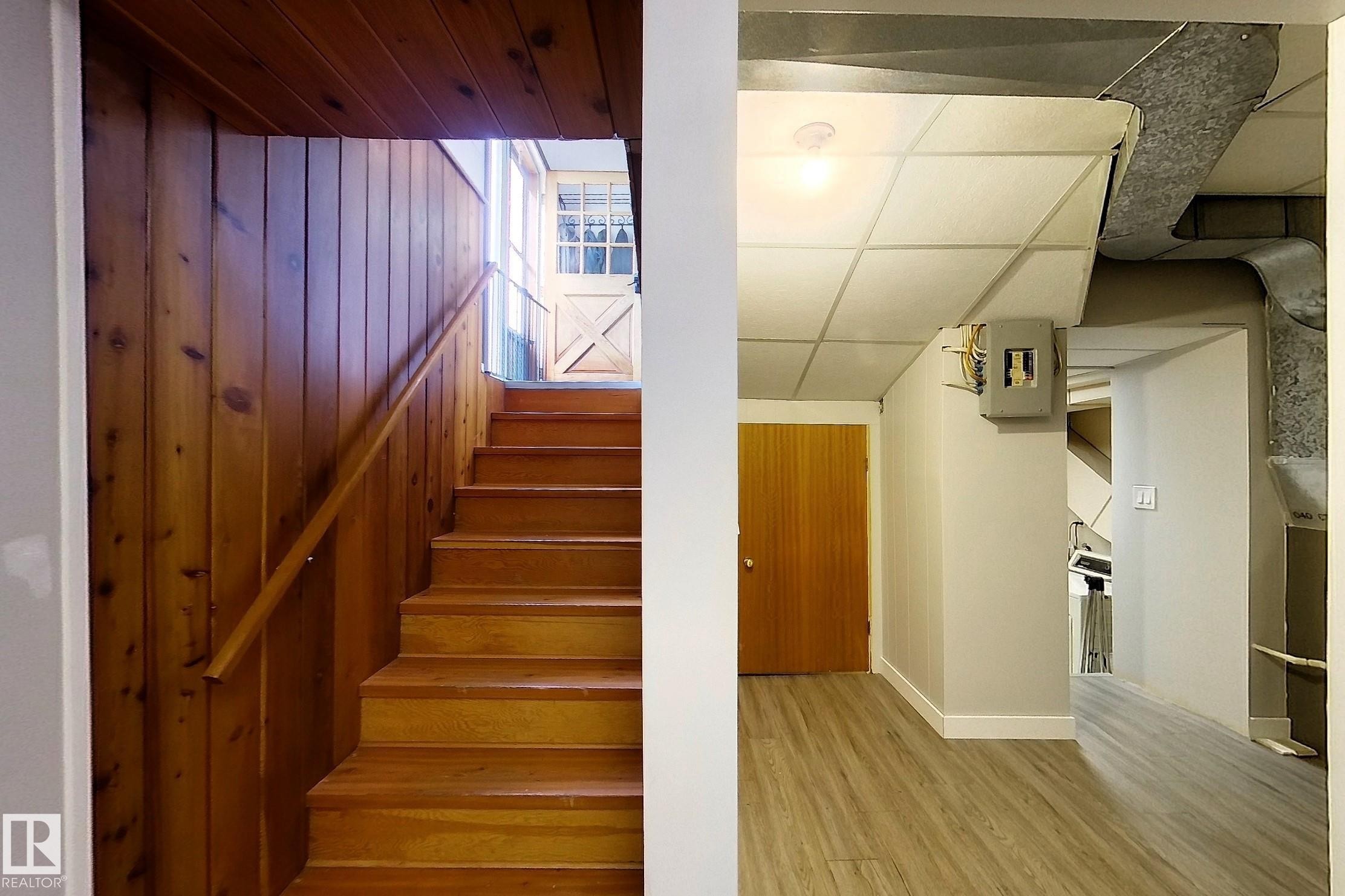 Wood-paneled staircase with a natural wood handrail and matching wood treads - 7126 4A Ave, Edson, AB - Indoor Photo Showing Other Room