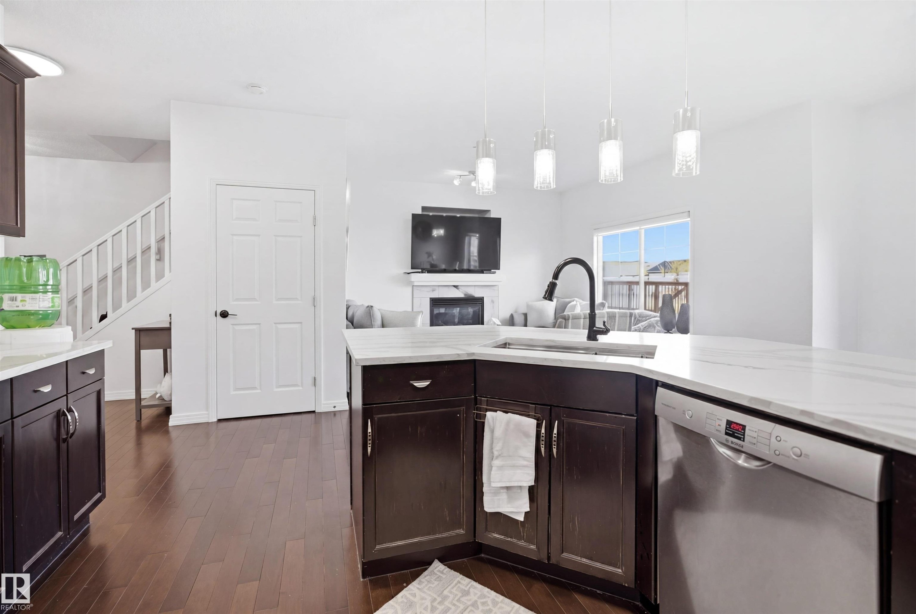 Kitchen featuring white countertops, dark wood-finish cabinetry, stainless steel dishwasher, and a gooseneck faucet - 1453 Hays Way Nw, Edmonton, AB - Indoor Photo Showing Kitchen
