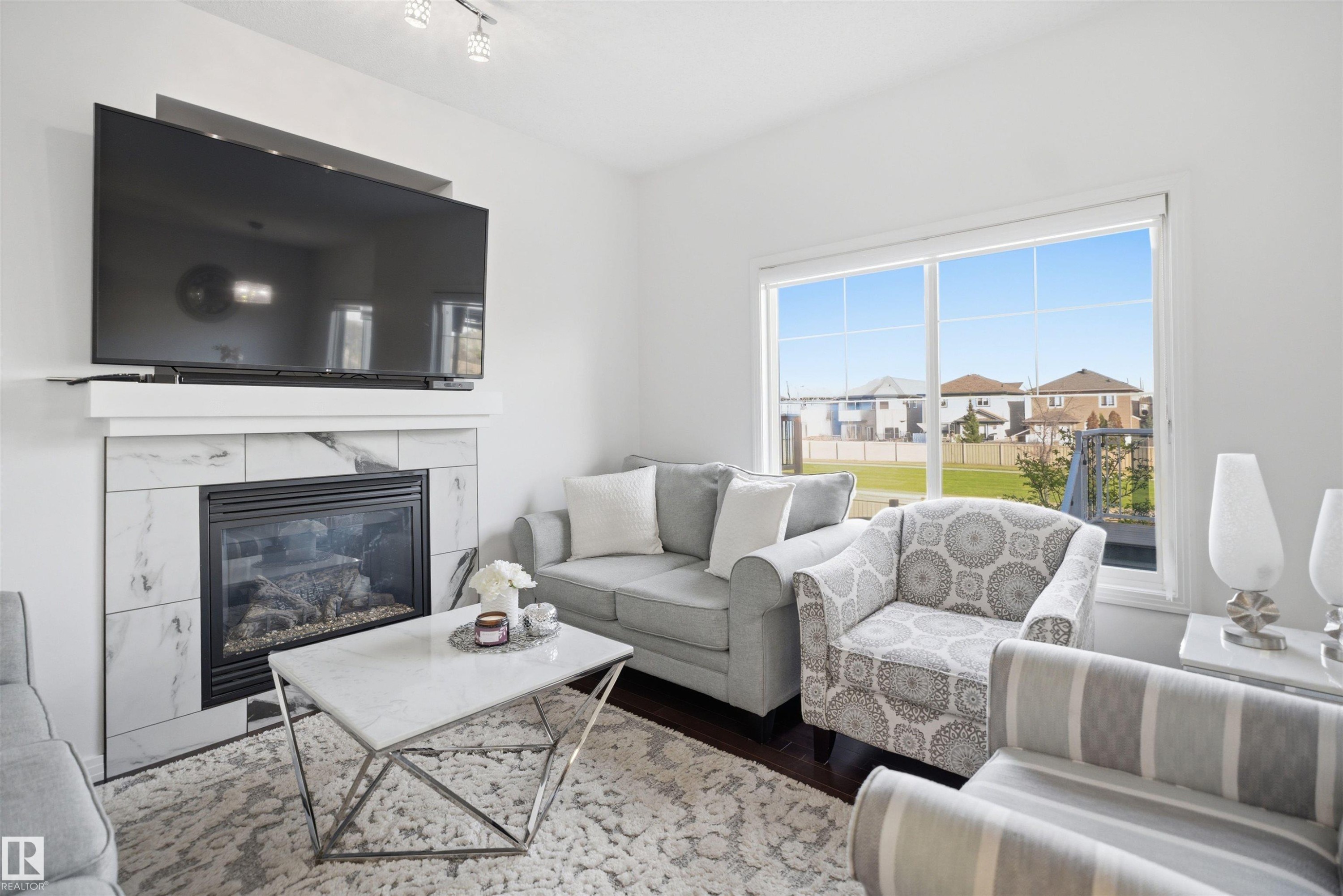 Living room featuring a gas fireplace with a marble-look tile surround and white mantel - 1453 Hays Way Nw, Edmonton, AB - Indoor Photo Showing Living Room With Fireplace