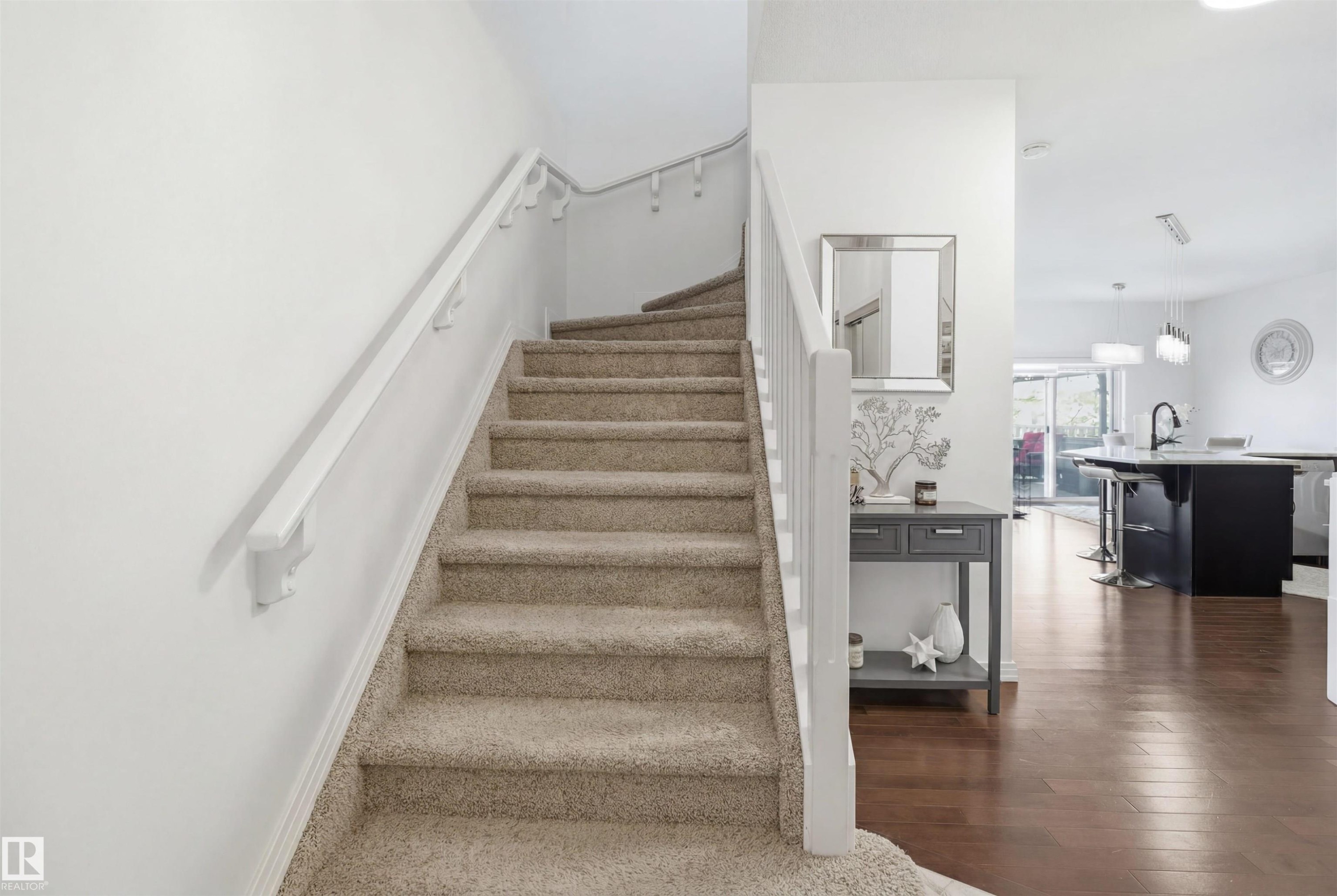 Carpeted staircase with white balusters and handrails, complemented by wood-finish flooring in the adjacent area - 1453 Hays Way Nw, Edmonton, AB - Indoor Photo Showing Other Room