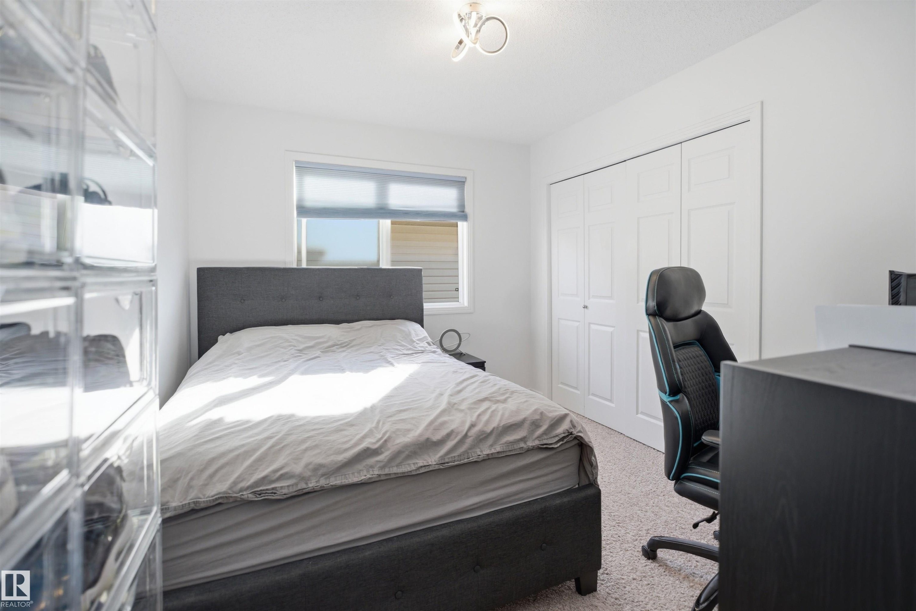 Bedroom featuring a window with roller shades, white walls, and light-colored carpet flooring - 1453 Hays Way Nw, Edmonton, AB - Indoor Photo Showing Bedroom