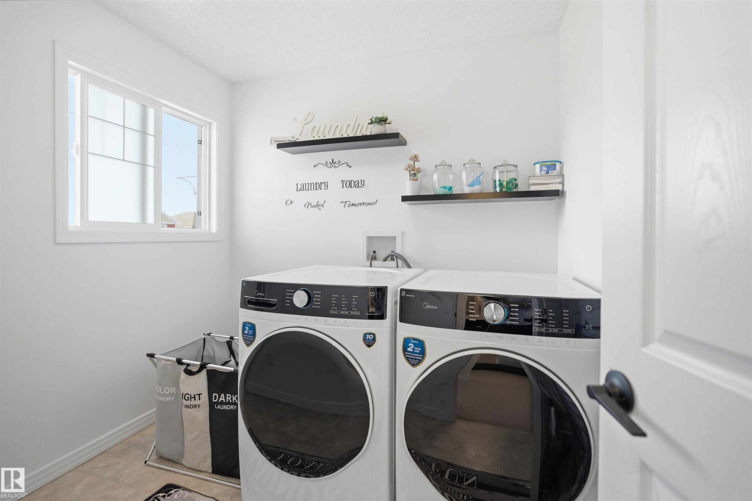 Dedicated laundry area featuring a window, built-in shelving, light-toned flooring, and white painted walls - 1453 Hays Way Nw, Edmonton, AB - Indoor Photo Showing Laundry Room