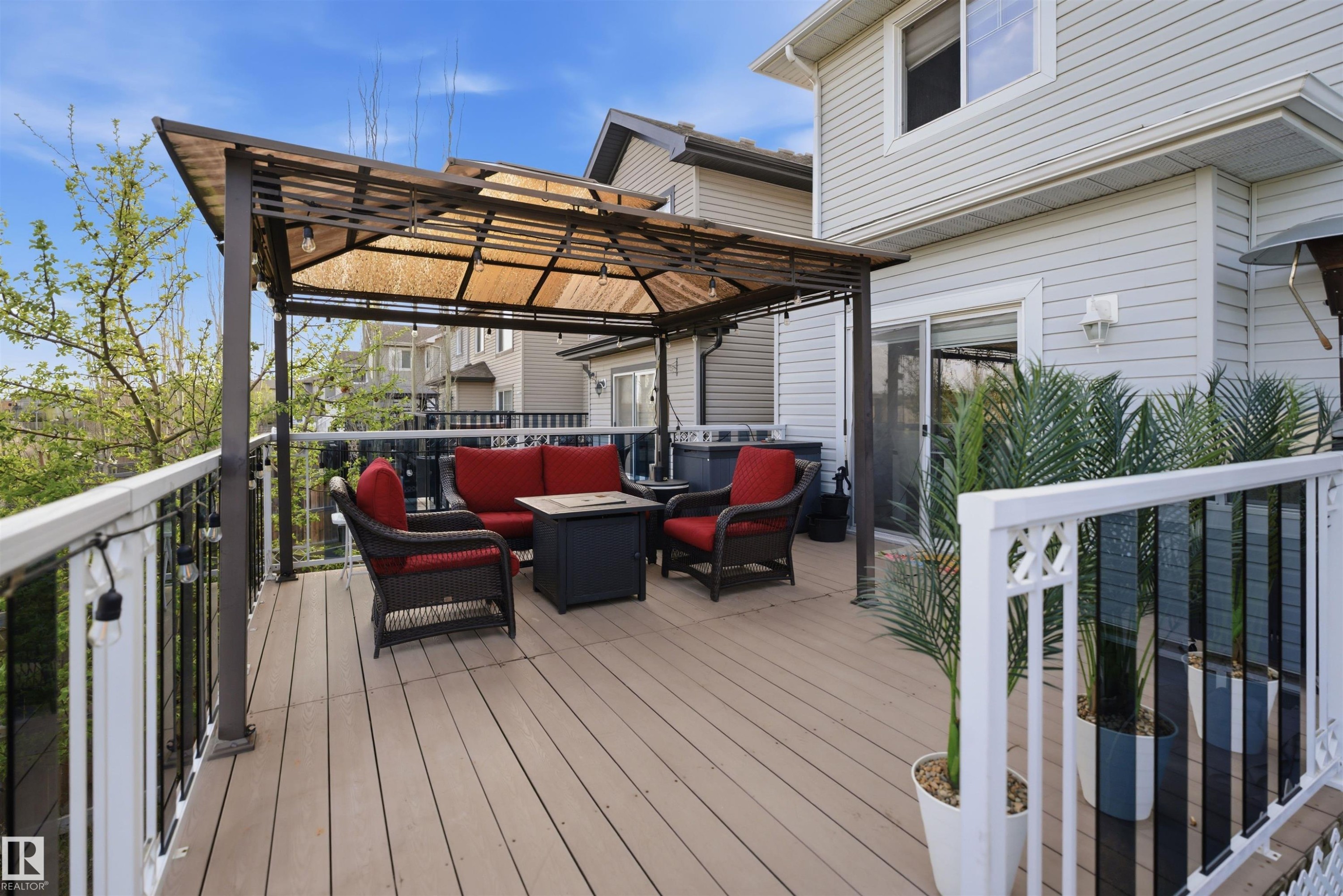 Expansive outdoor deck featuring wood-finish flooring, a pergola with a translucent canopy, white and black railings, and direct access to the interior via a sliding glass door - 1453 Hays Way Nw, Edmonton, AB - Outdoor With Deck Patio Veranda With Exterior