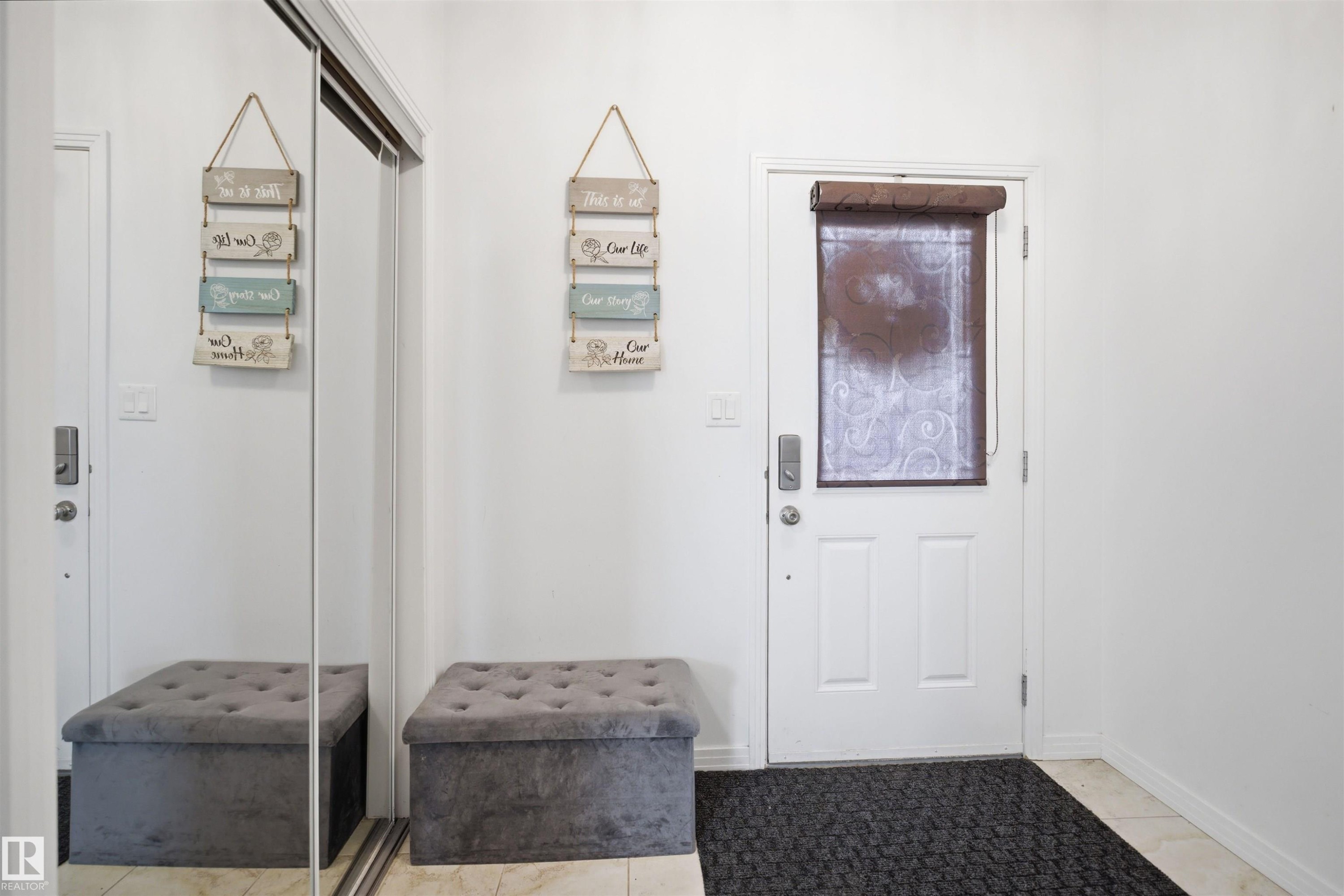 White entry door with decorative glass panel, ceramic tile flooring, and sliding mirrored closet doors - 1453 Hays Way Nw, Edmonton, AB - Indoor Photo Showing Other Room